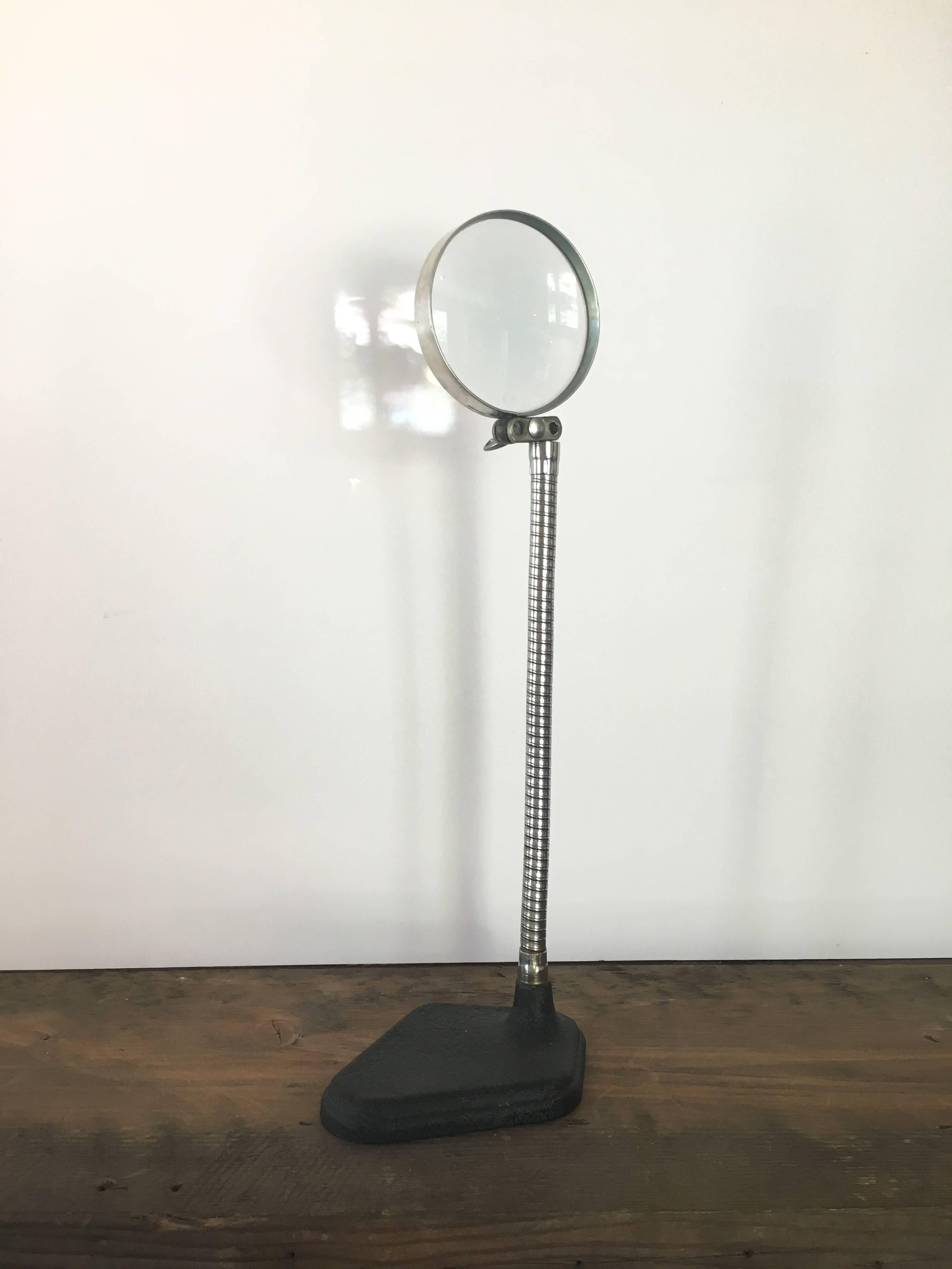 Free-standing vintage magnifying glass. American, circa 20th century. Curving articulated arm on pebbled black base.