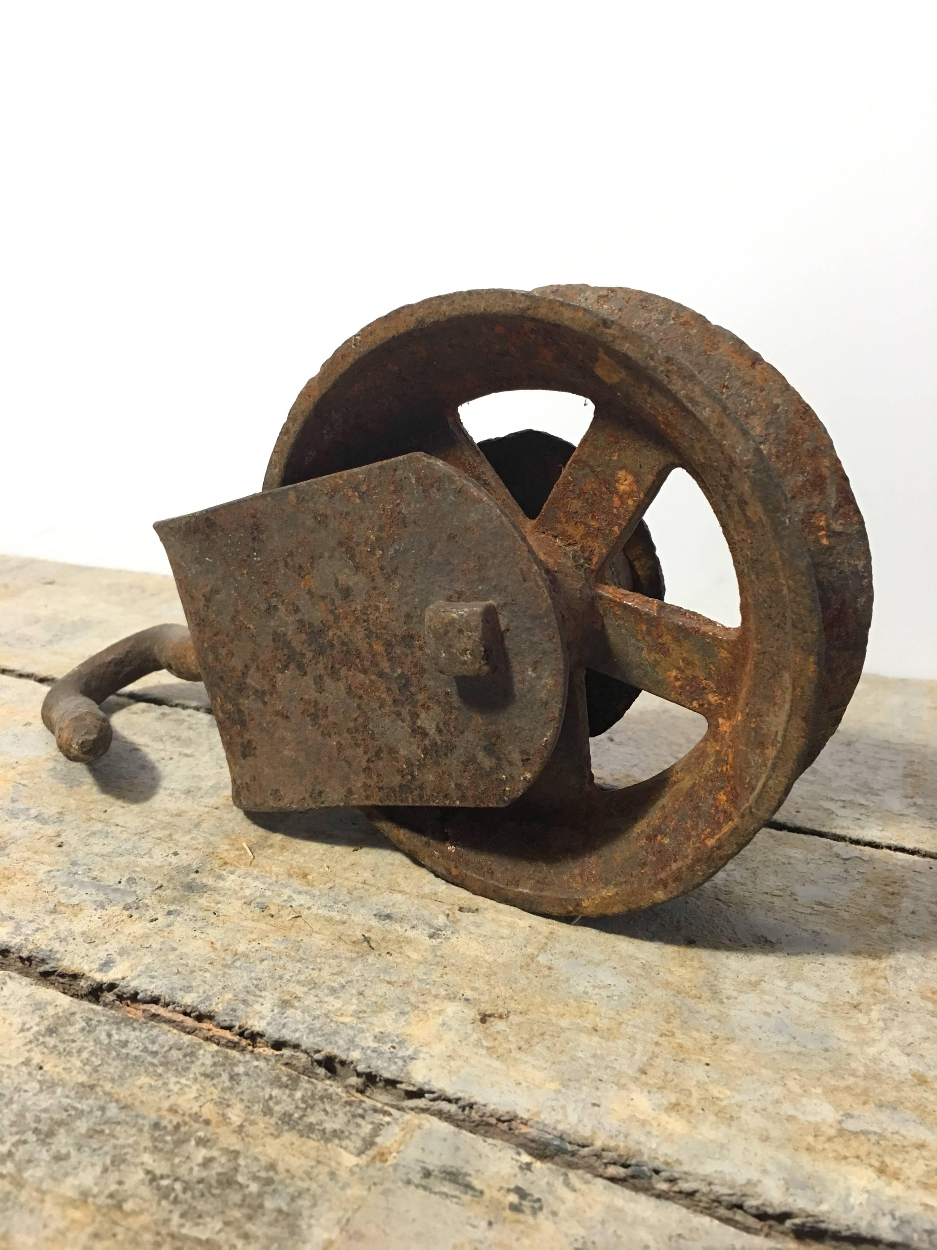 Antique single metal pulley with a hook. Minor wear consistent with age and use.