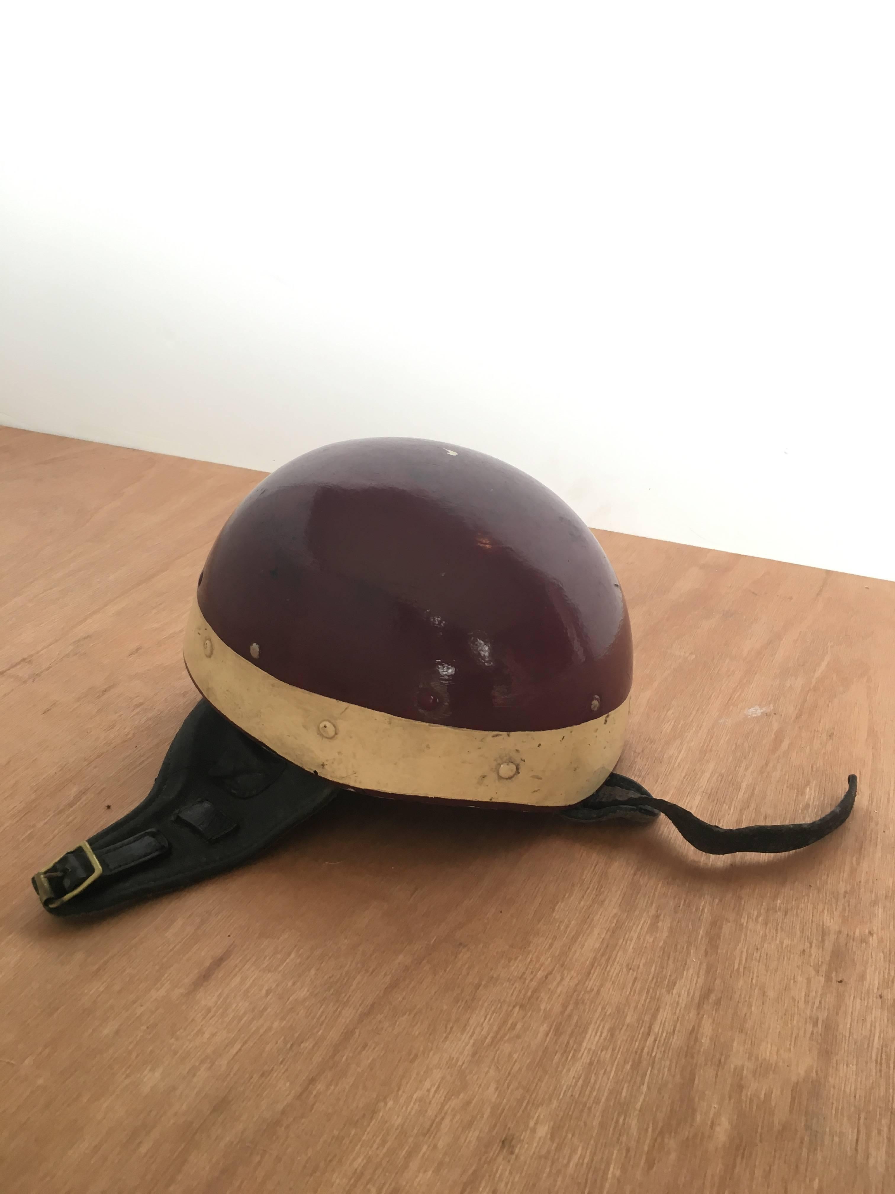 Vintage burgundy riding helmet with chin strap.