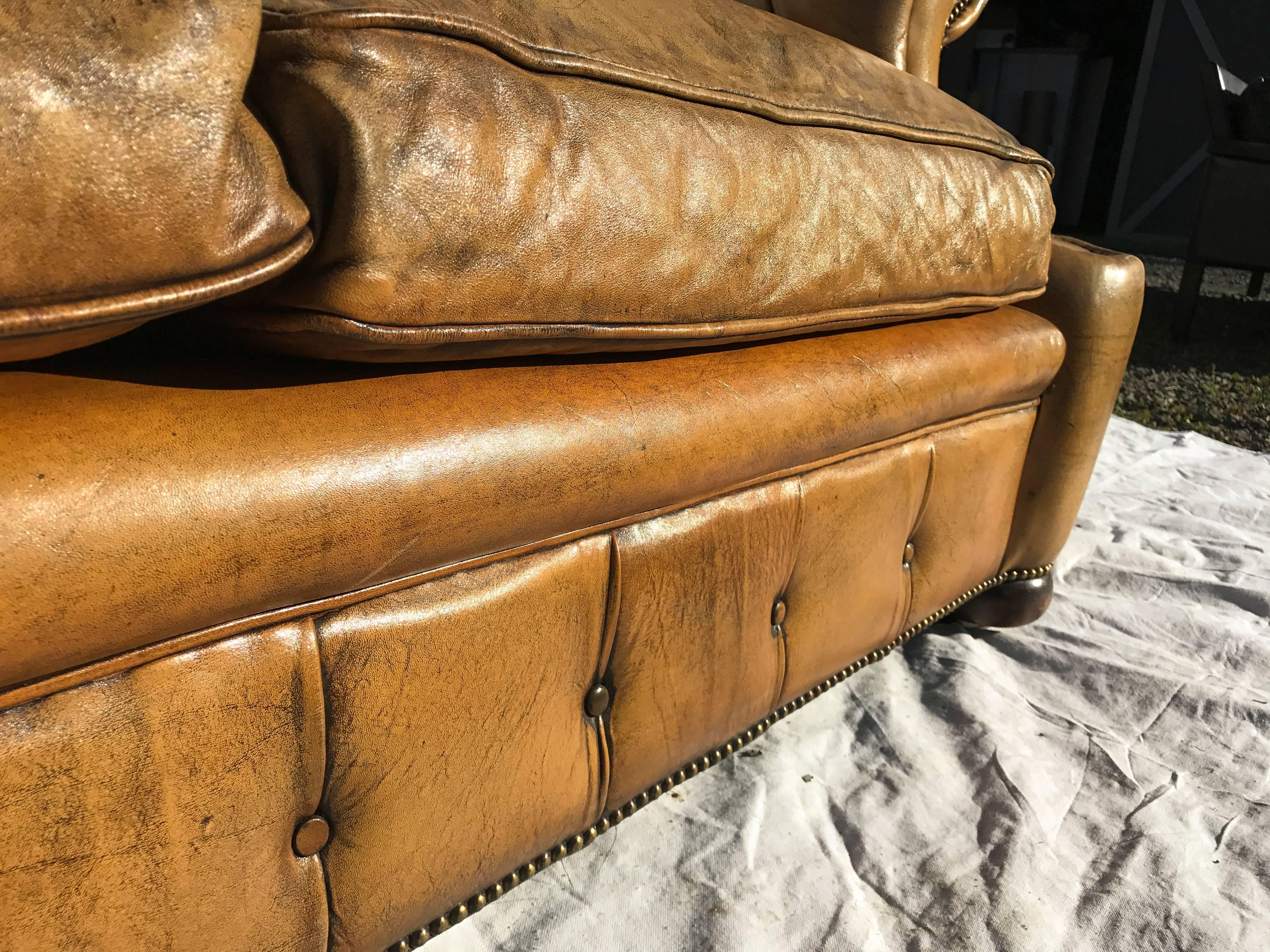 Early 20th century leather Chesterfield sofa with curved armrests and a tufted back. Cognac leather and brass nailheads, both with a beautiful patina.
 