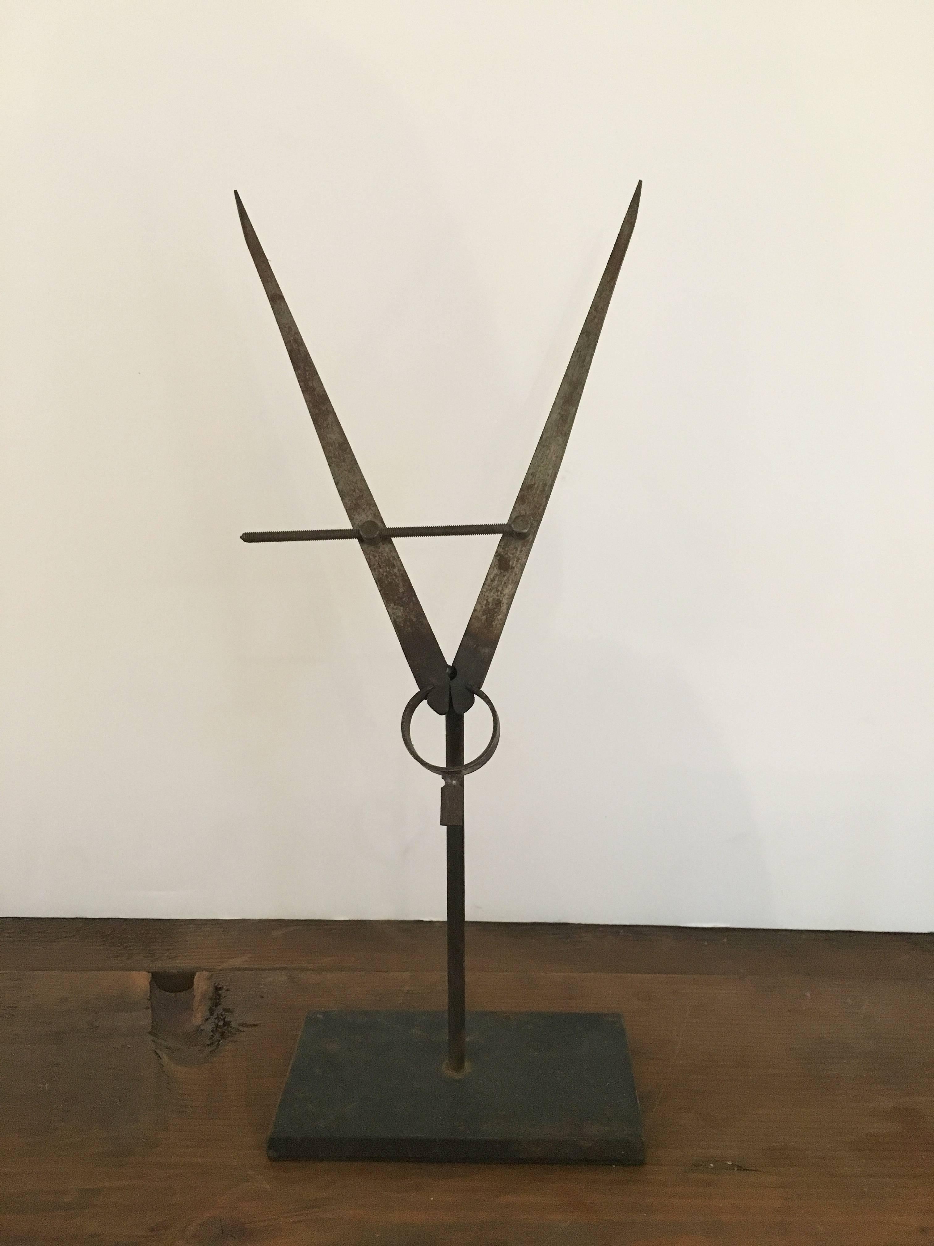 Mounted vintage drafting compass. 

Historical drafting tool welded to steel base, for presentation as sculpture, in library, work shop, or cabinet of curiosity.