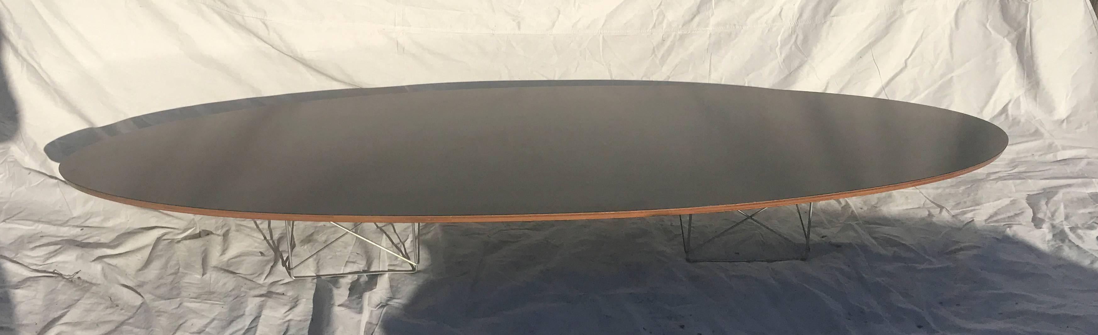 Elliptical Table Rod (ETR) - Original Eames Elliptical Table with Rod base often referred to as the Surfboard table due to its elongated shape and low profile. Elle utilise deux des bases en fil de fer conçues pour les tables LTR, qui supportent un