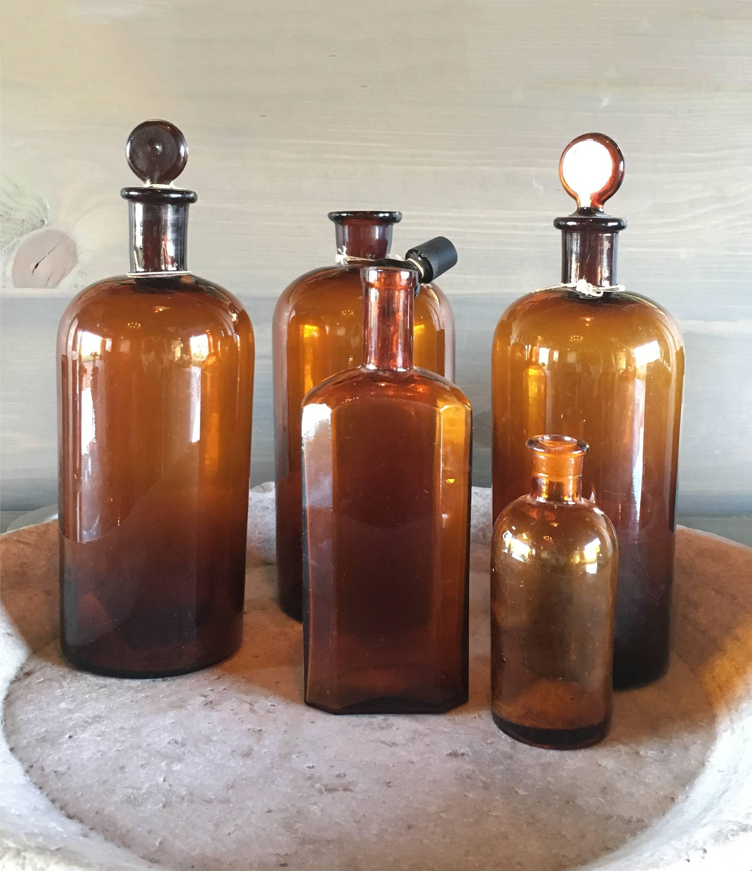 Set of five amber glass vintage apothecary bottles, France, circa 19th century. 

Three large bottles with stoppers, a medium-sized rectangular bottle, and one small cylindrical smaller bottle. 

Originally for storage of medicinal or