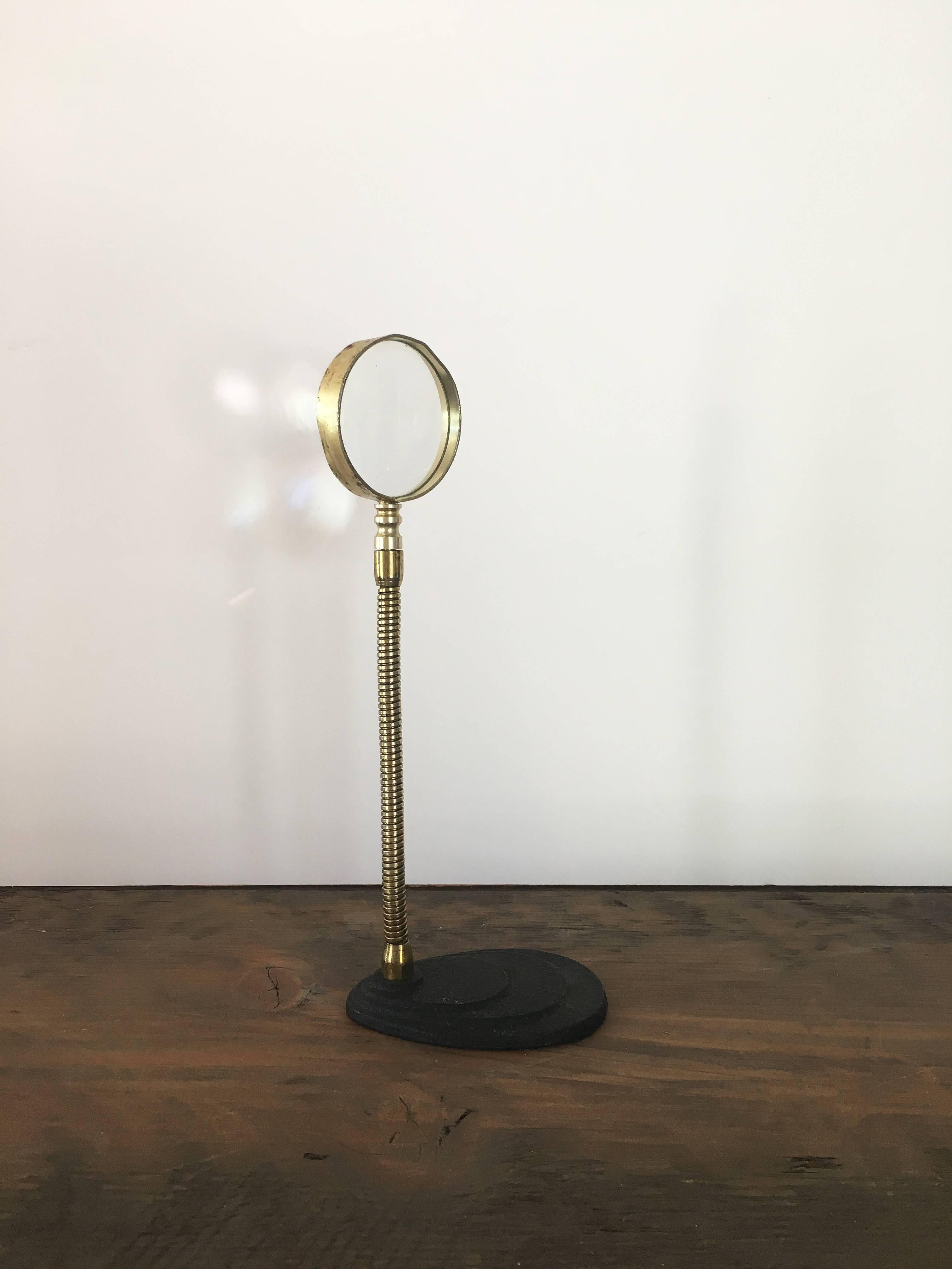 Free-standing vintage gooseneck magnifying glass on a scalloped black metal base. 

Metal with brass finish; a few dents; wear according to age and use.