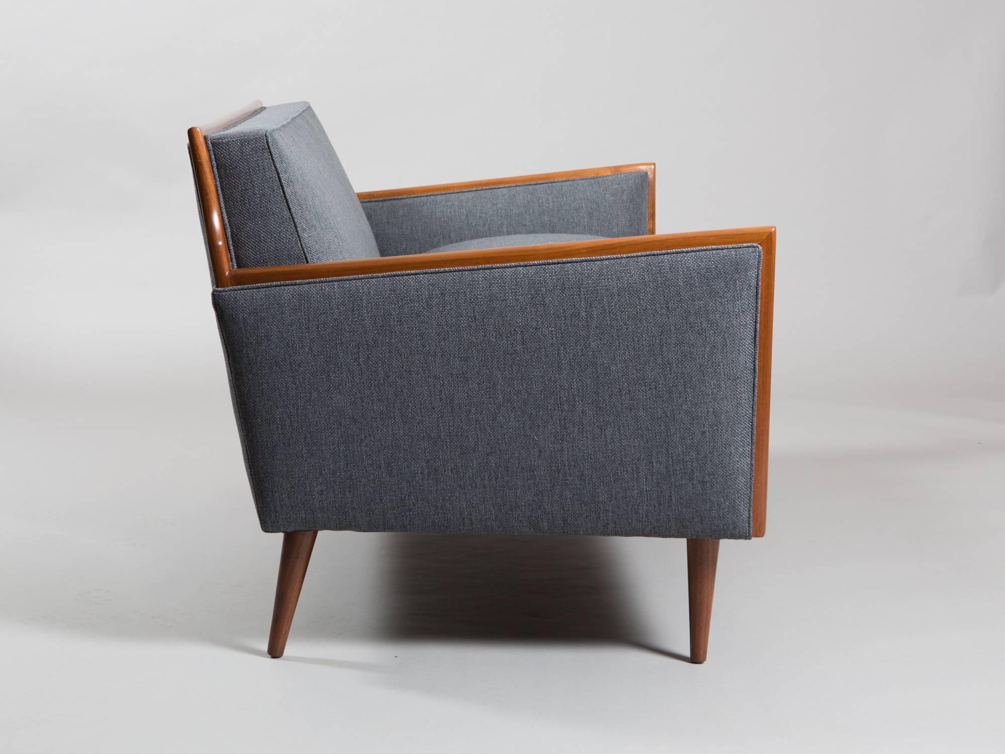T.H. Robsjohn-Gibbings style sofa with wooden trim detail, tapered legs and straight back. Stylish and clean Mid-Century design. Newly restored and upholstered.
Measures: Seat width 50