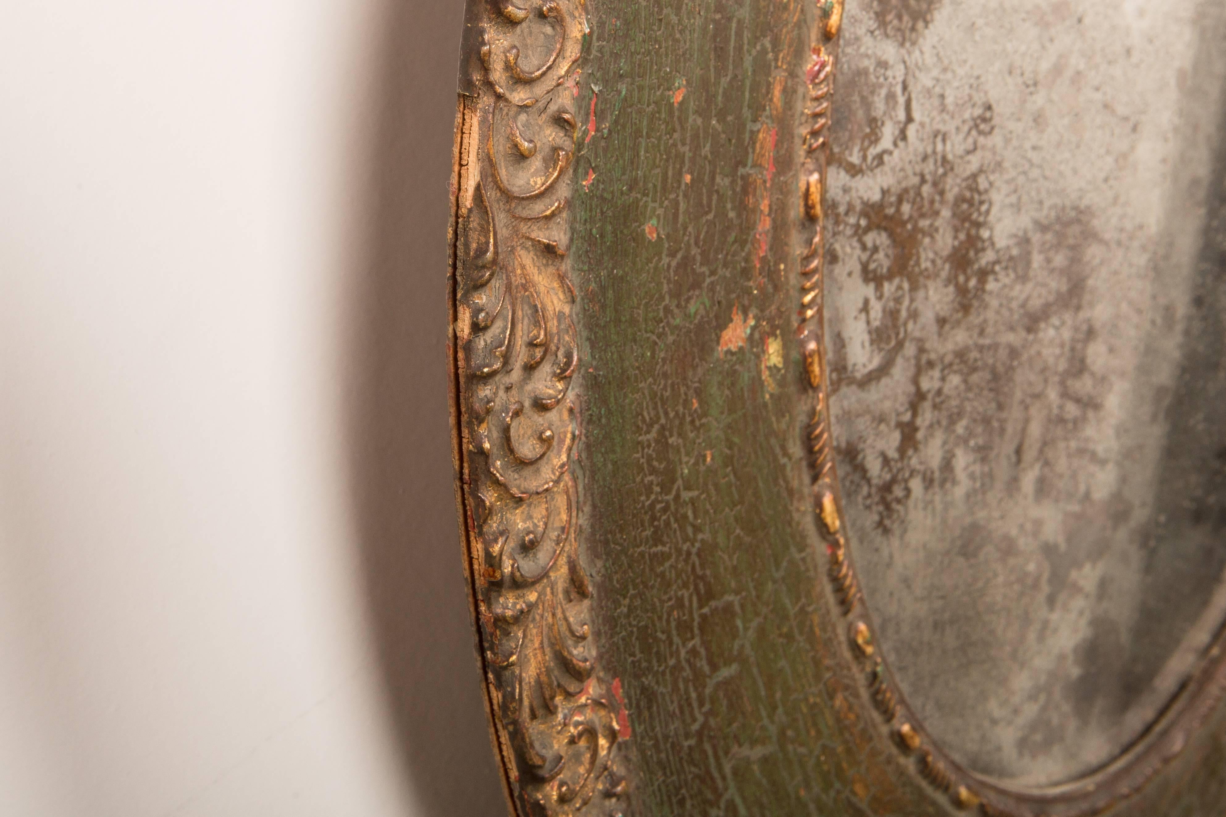 Pair of gorgeous 19th-Century antique oval mirrors with unbelievably beautiful patination to the original mirror. Faded gilt on the edge carving detail, and a wonderful shade of deep green. Some losses and chipping throughout. These mirrors have age