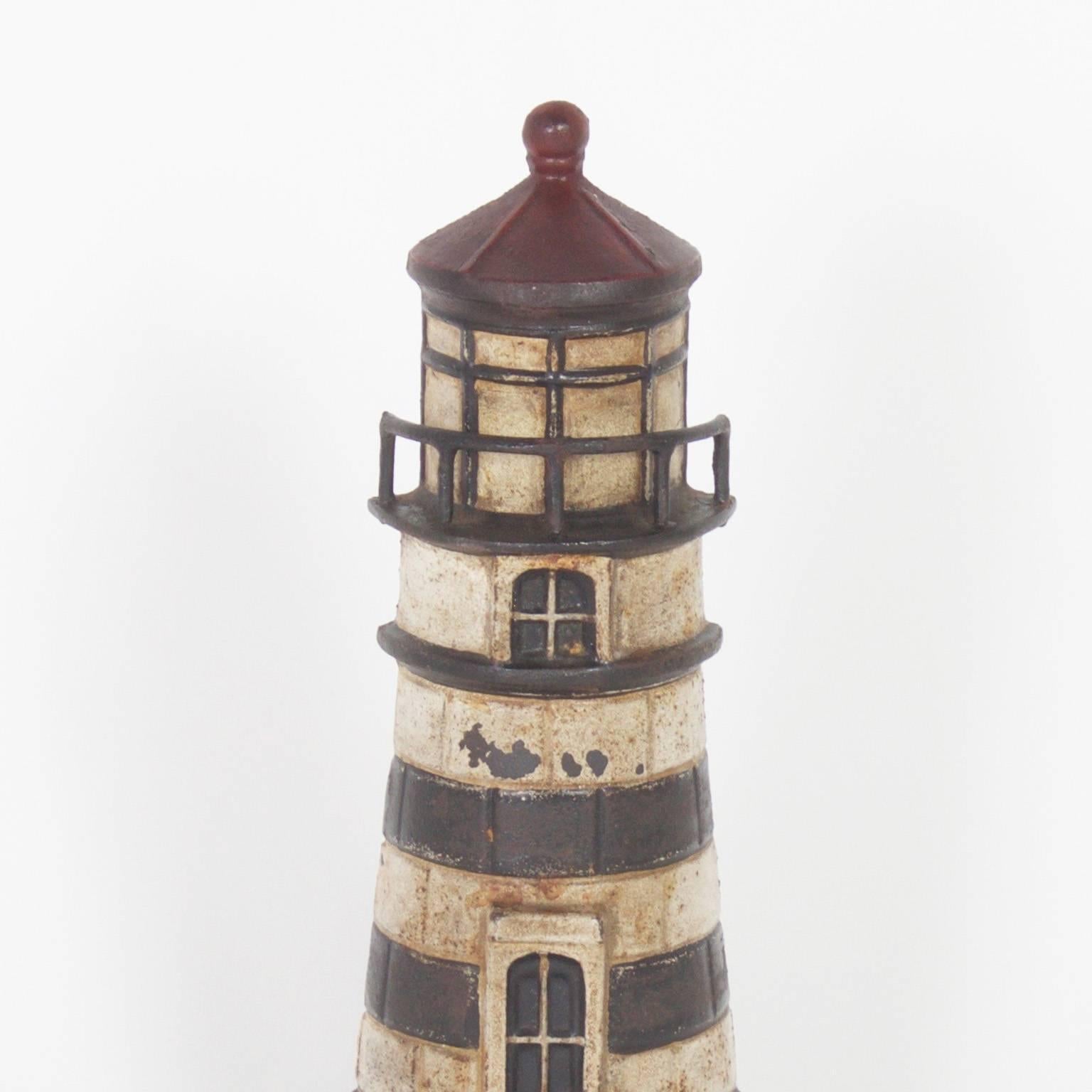 Antique cast iron doorstop depicting a classic piece of coastal architecture and with its original paint, which has become charmingly time worn. Add it to your collection of lighthouses or use it to stop a door.

.
  