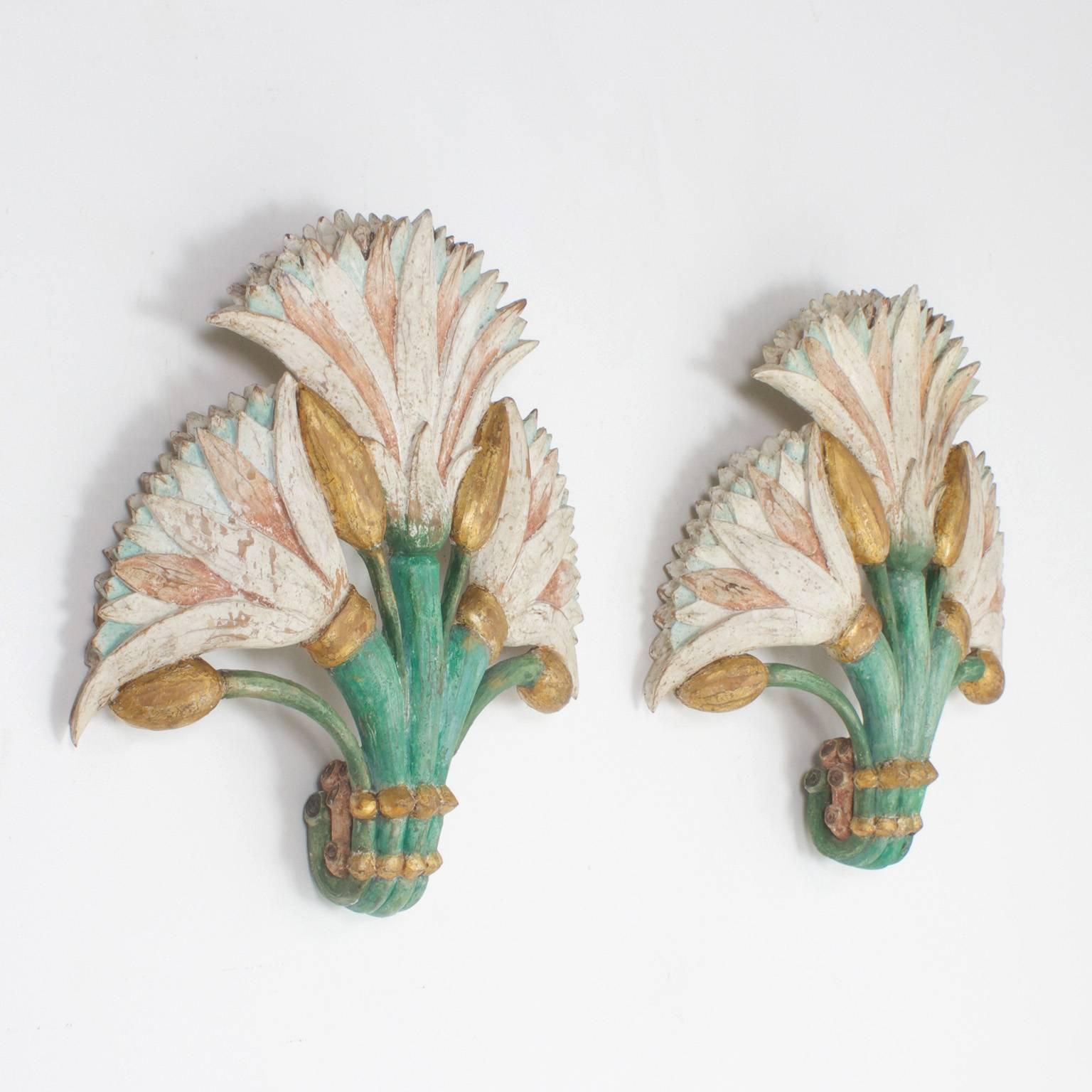 Pair of exotic Italian floral carved wood wall hangings or wall decorations, retaining their original, now time worn, green, white, pink and gold paint. These inspired carvings have a sense of enlightenment that gets attention in a subtle way.

