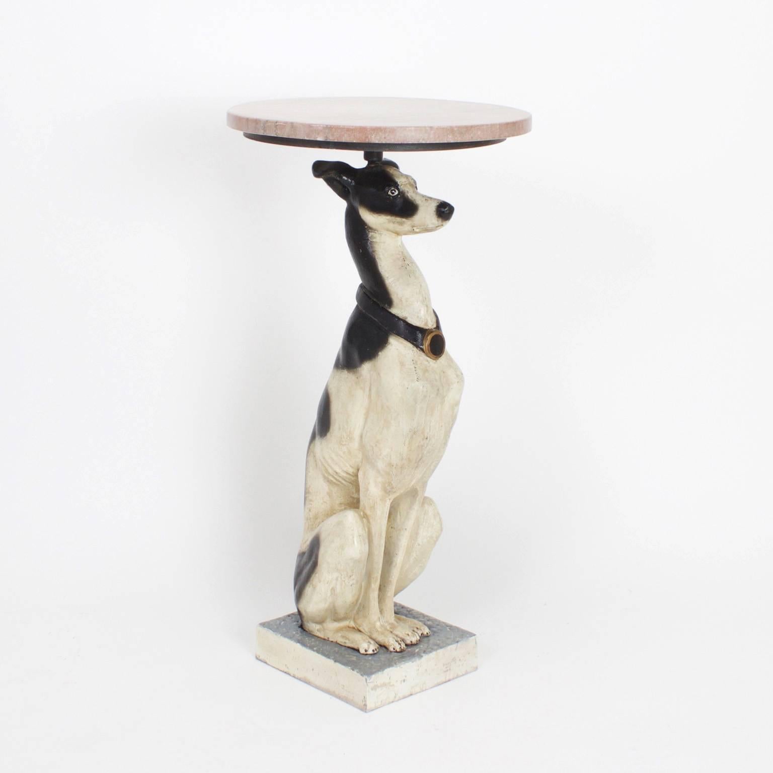 Pair of iron whippets or greyhound tables with realistic physiques decorated with rustic white and black paint. These dogs, now in service as stands, are sporting swank collars and quirky expressions. The tops are rouge marble.

.
  