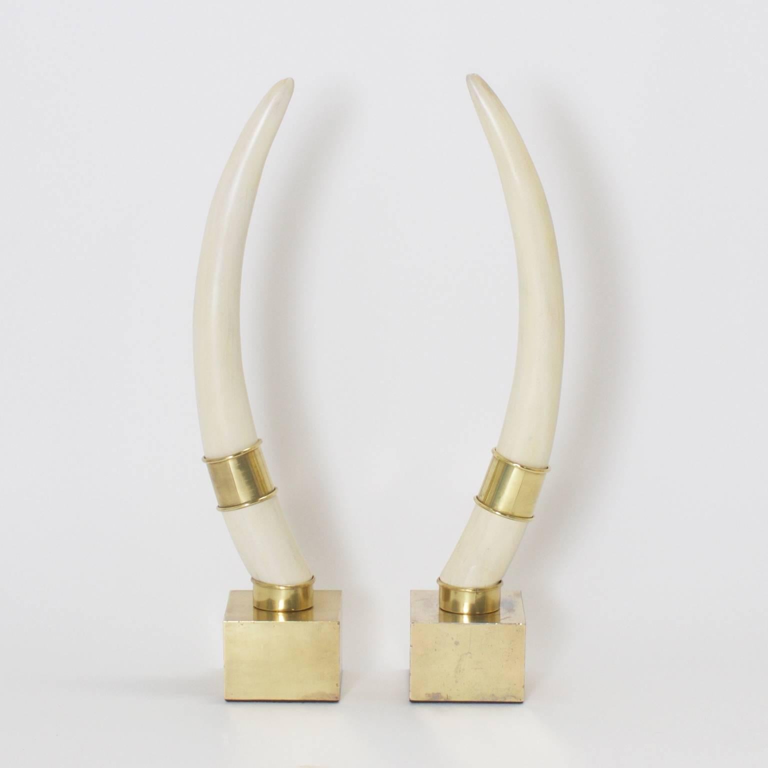 Pair of Mid-Century eco-friendly carved wood faux walrus tusks, mounted on brass cubes with matching polished brass rings. Old world concept with a modern image.
 