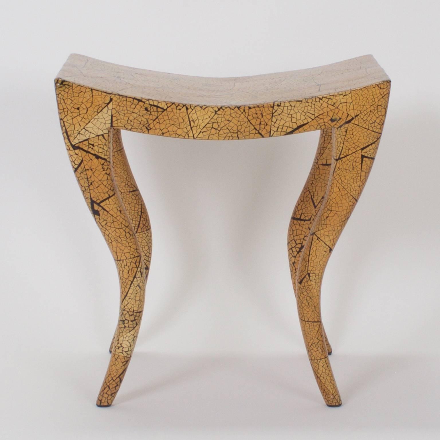 Swank midcentury bench or stool with a dramatic Egyptian influenced form and a hip crackled finish in variegated organic colors. Signed on a proper English brass tag 