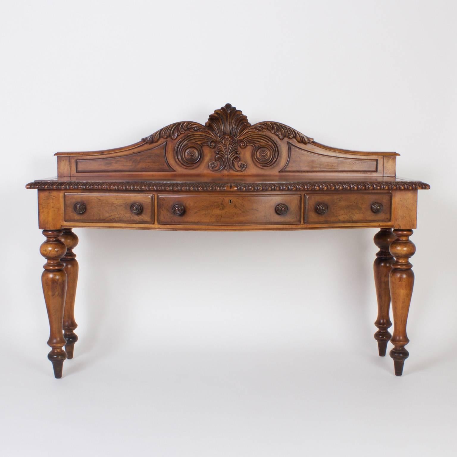 Impressive, British colonial style sideboard or server with an inspired bold presence. Expertly crafted in walnut and featuring an elaborately carved gallery and a bow front case with three drawers set on Classic turned legs. Reminiscent of West