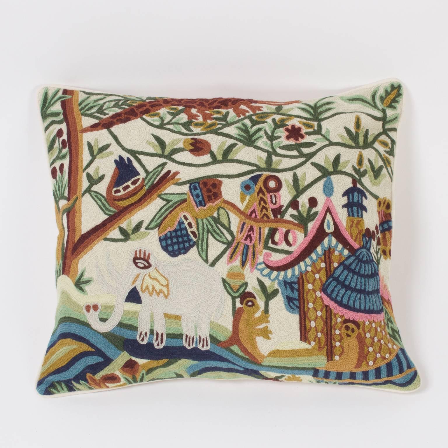 Pair of handcrafted crewel pillows with a whimsical point of view depicting an elephant, monkey, birds, lizard, flowers and trees all living harmoniously around a simple home.
  