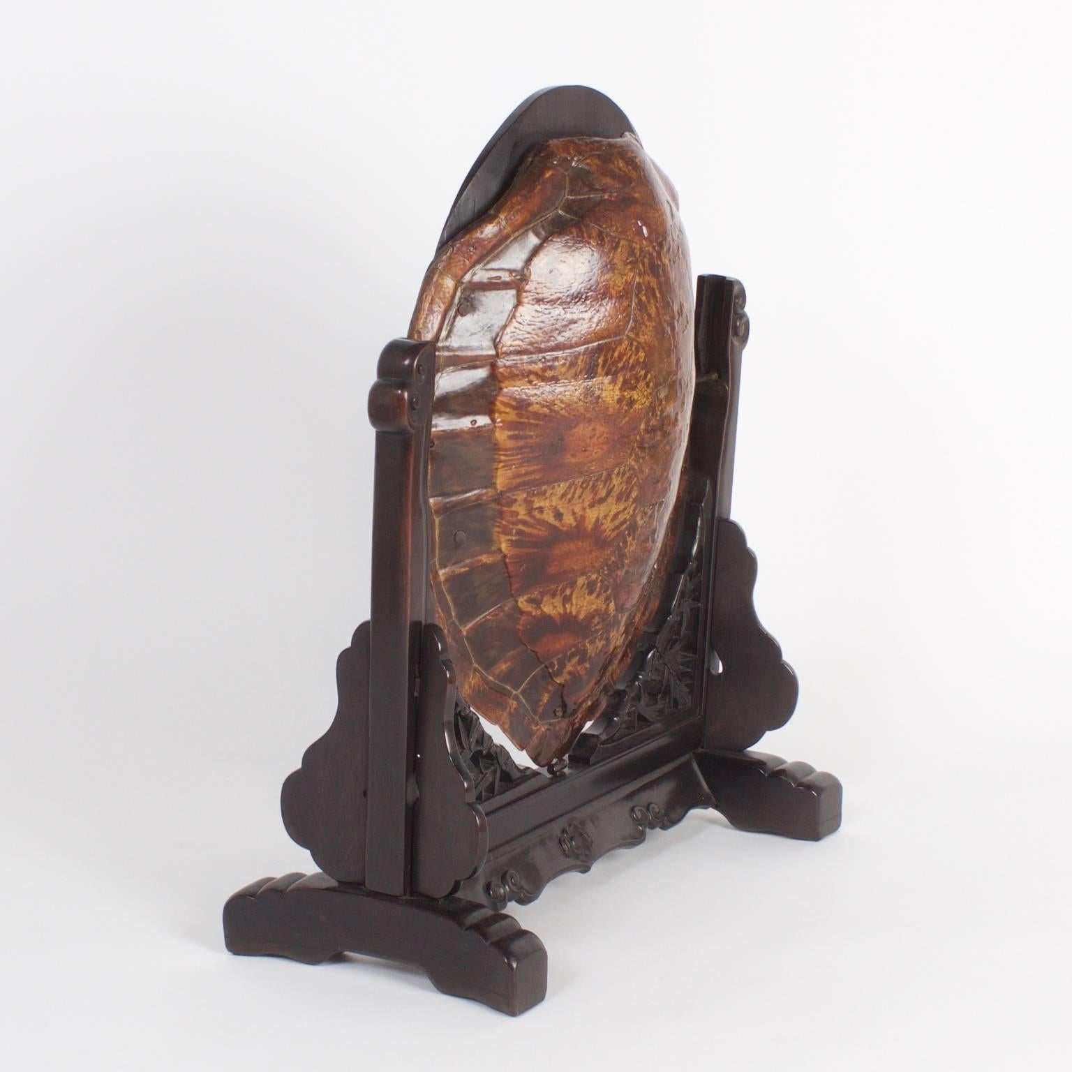 Here is a rare and unusual antique, Chinese vanity mirror presented in a turtle shell. The mirror is in a mahogany frame, expertly carved with lotus flowers and mounted in a carved mahogany stand. We will all probably never see another object of art