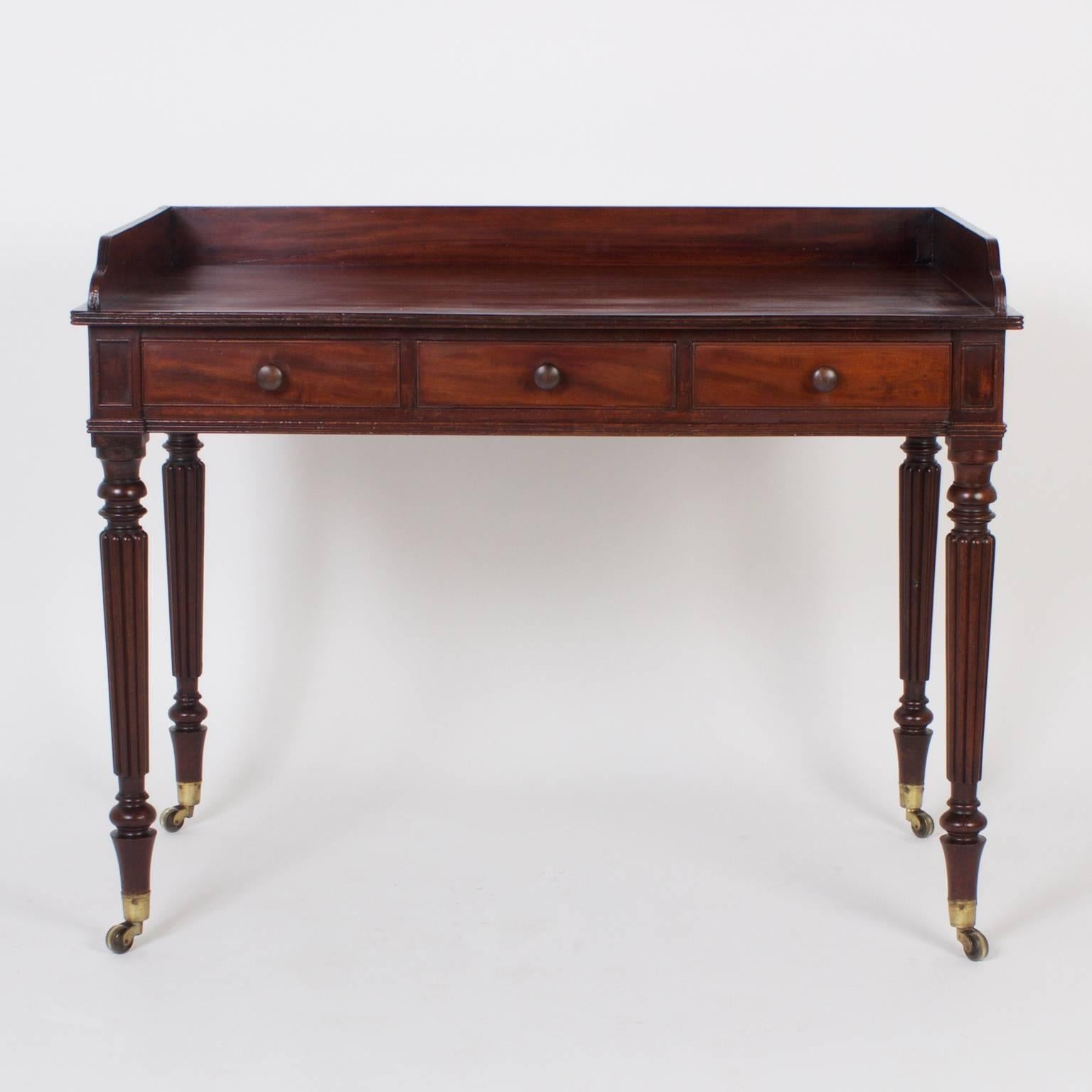 Fine, antique English server or bar expertly crafted with mahogany. Featuring single construction on top, a simple gallery, three storage drawers, elegant turned and reeded legs all on brass casters. Perfect proportions and well grained woods