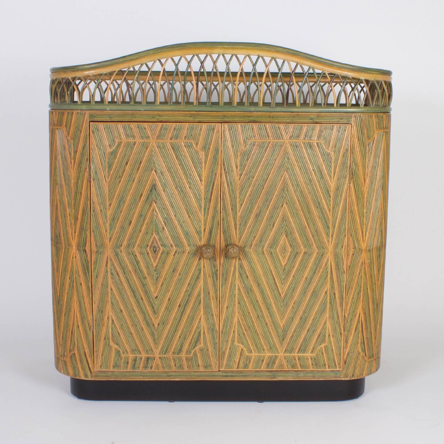 Stand out Art Deco rattan or wicker bar or server decorated with reed in a sophisticated geometric design. Featuring a gallery on top, two cabinet doors in front, plenty of storage and an ebonized block foot. A rare and unusual piece probably custom