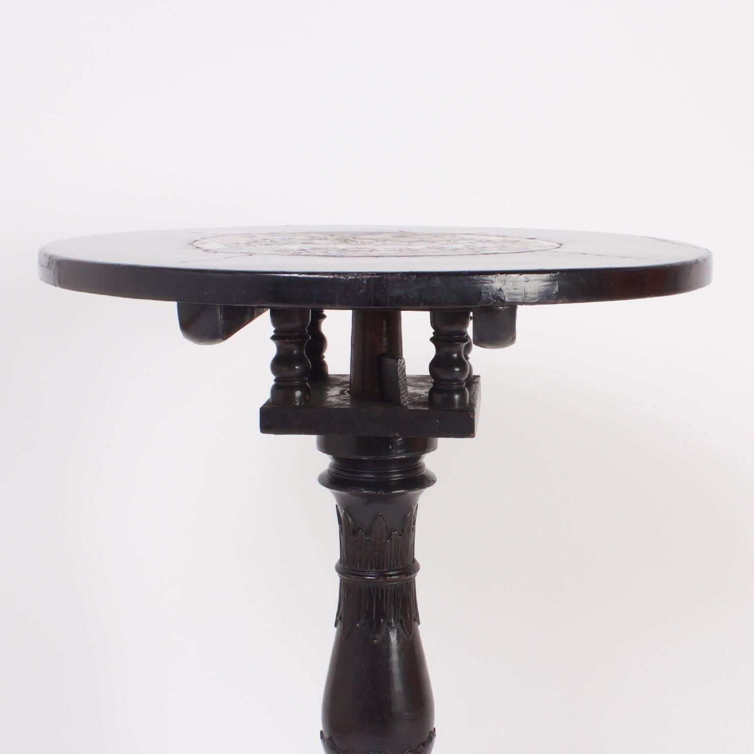 Rare chinese carved rosewood table or candle stand with an ebonized finish. The top features an inserted porcelain plaque in the Chinese Export manner, depicting a colorful scene from the forbidden city. The carved pedestal base is supported by