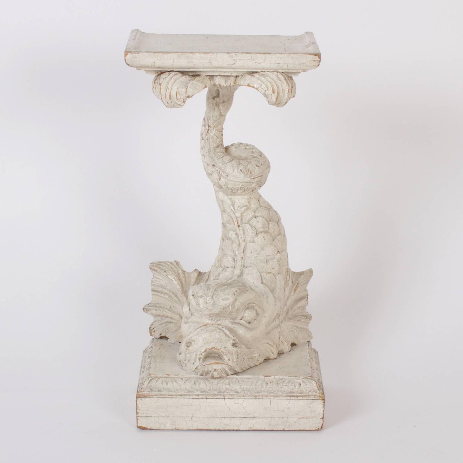 Antique carved wood drink stands or tables depicting mythological dolphin like sea creatures, in service supporting trays and mounted on classical plinths. Retaining their original paint which has acquired a charming aged finish.