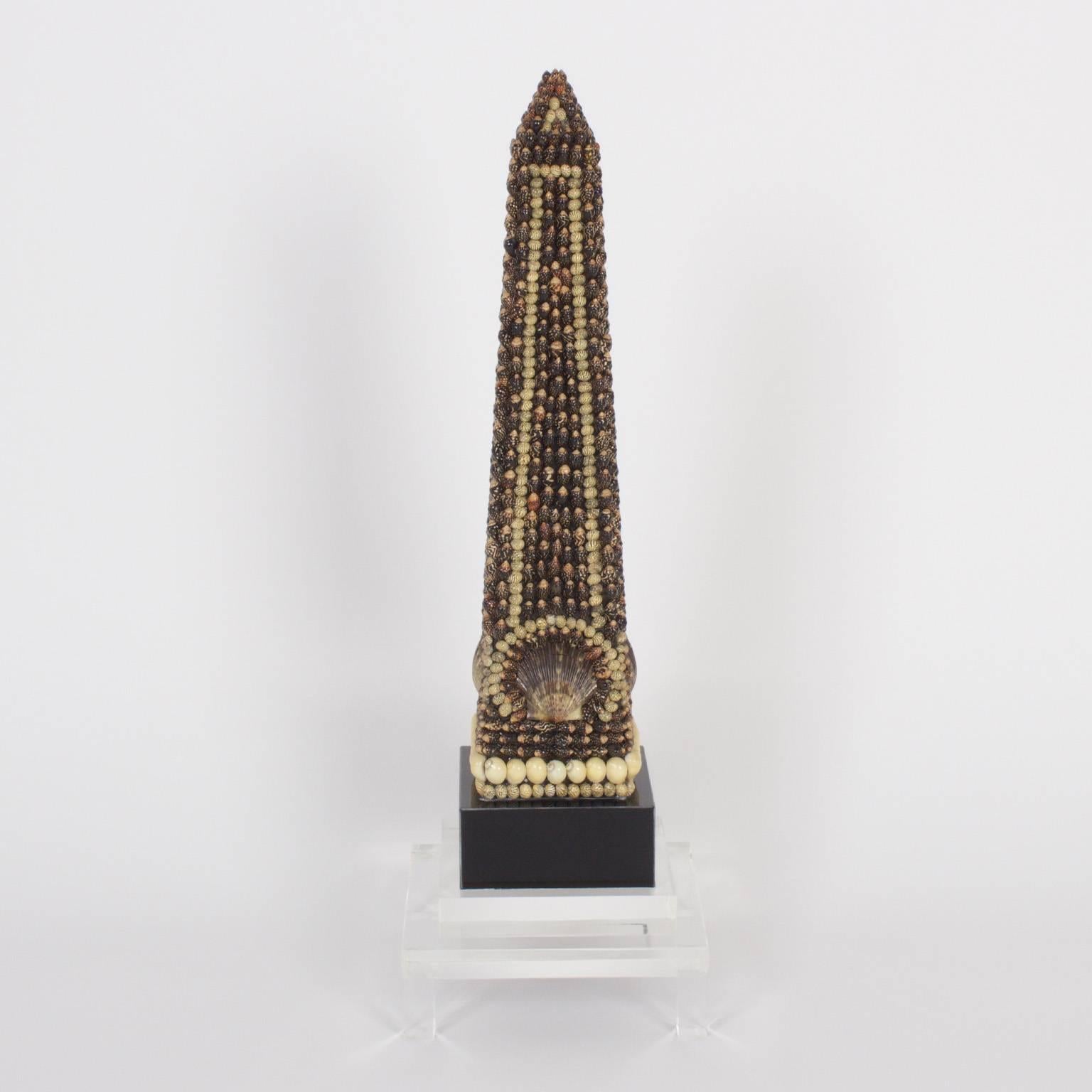 The iconic architectural form of the obelisk, here encrusted in a sophisticated design, with exotic seashells, mounted on ebonized bases and presented on Lucite stands.
 