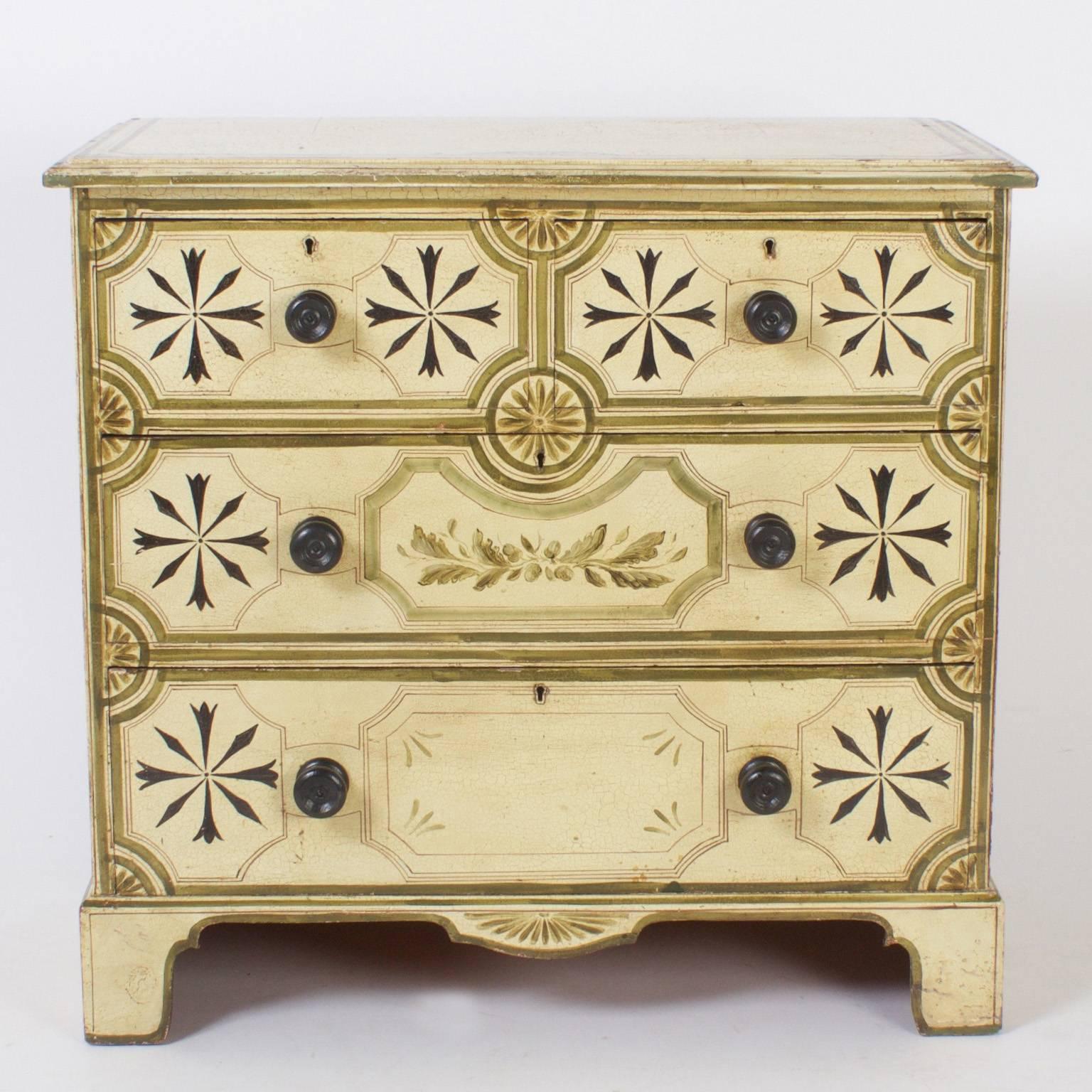 Charming, vintage cottage chest of drawers painted with a crackled ivory background and decorated with geometric and floral designs. The case is a simple Georgian form on dramatic bracket base.