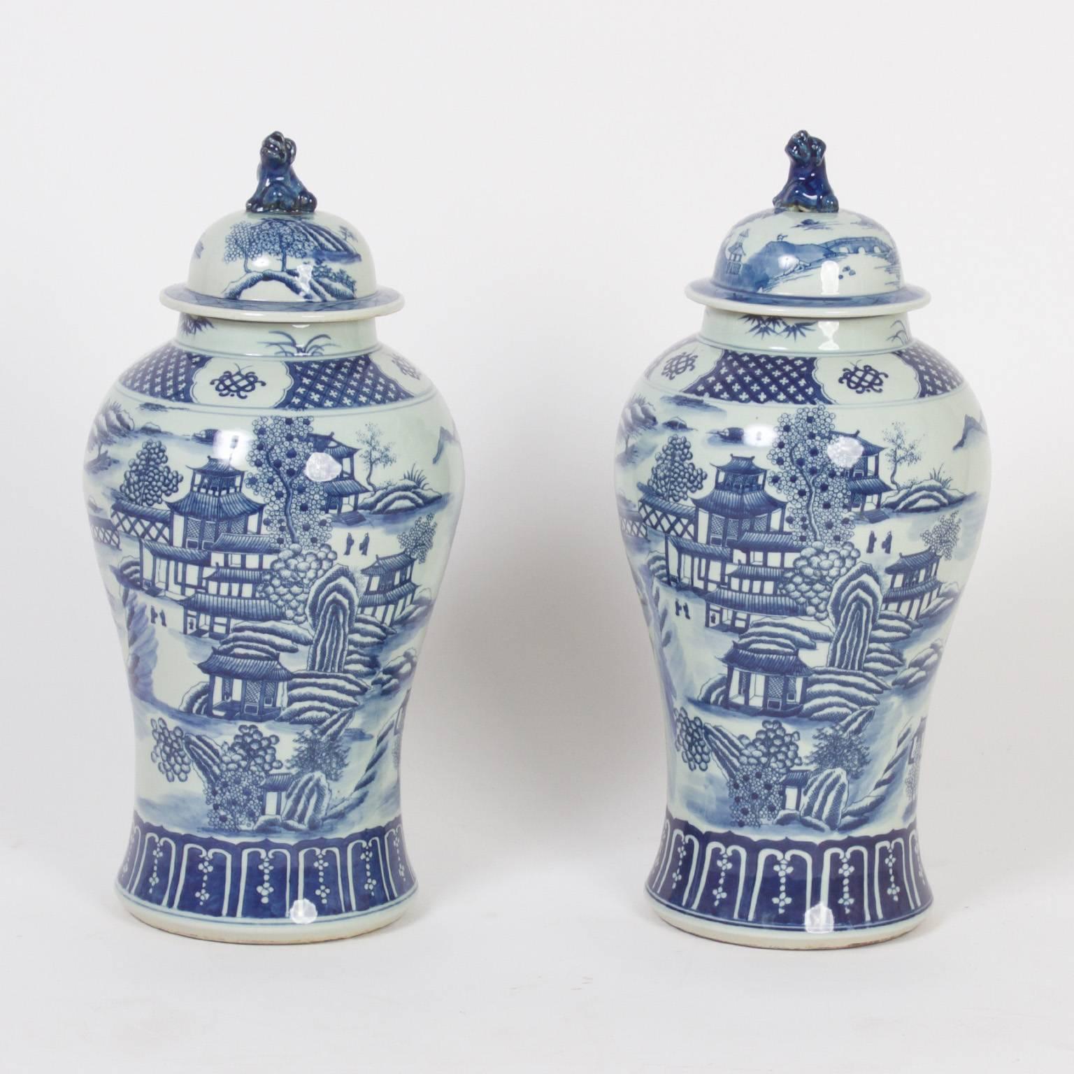 Traditional Chinese export style blue and white porcelain lidded jars decorated in blue and white with landscapes, architectural examples and bordered in geometric patterns.
 
 