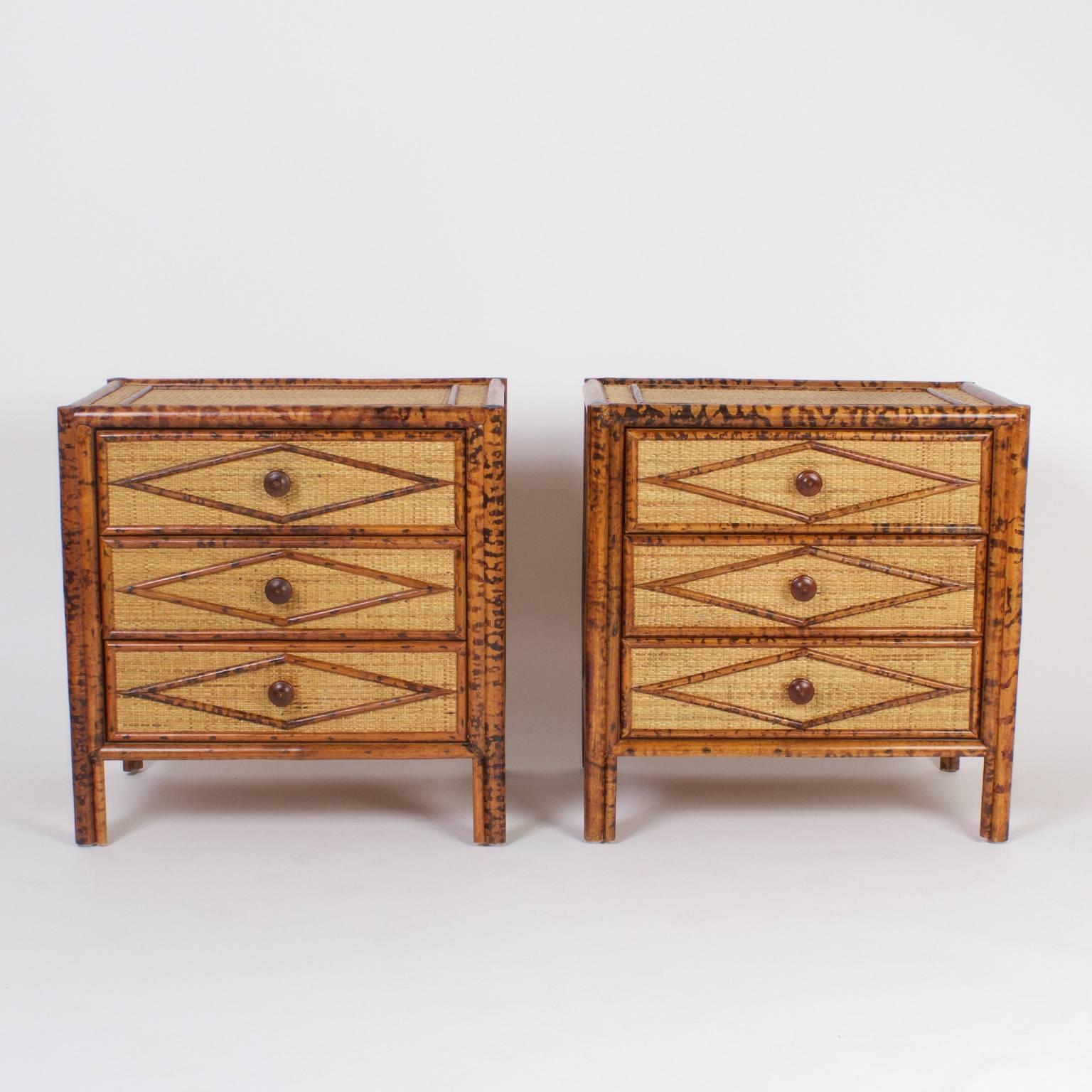 Pair of three drawer rattan nightstands or chests with a lush tropical ambiance that is modern yet warm. The case is covered with grass cloth and the frame is hand painted tortoiseshell faux bamboo. The sides and drawers have applied geometric