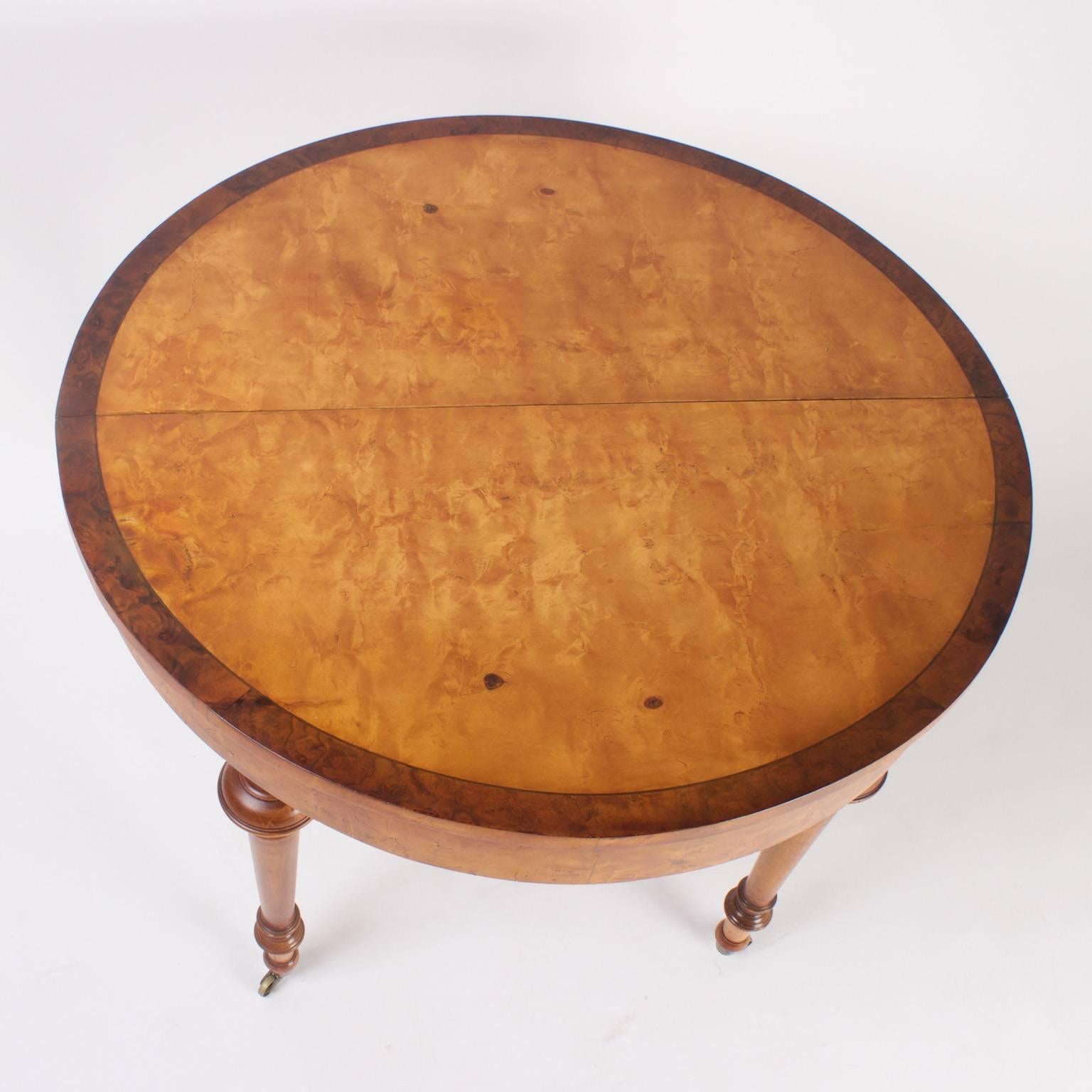 Impressive Napoleon III dining table with a rare burled maple top banded in burled walnut. The five turned legs are also maple set on brass casters. Pictured as a round table which could be used as a center table or dinette.  Also pictured with one