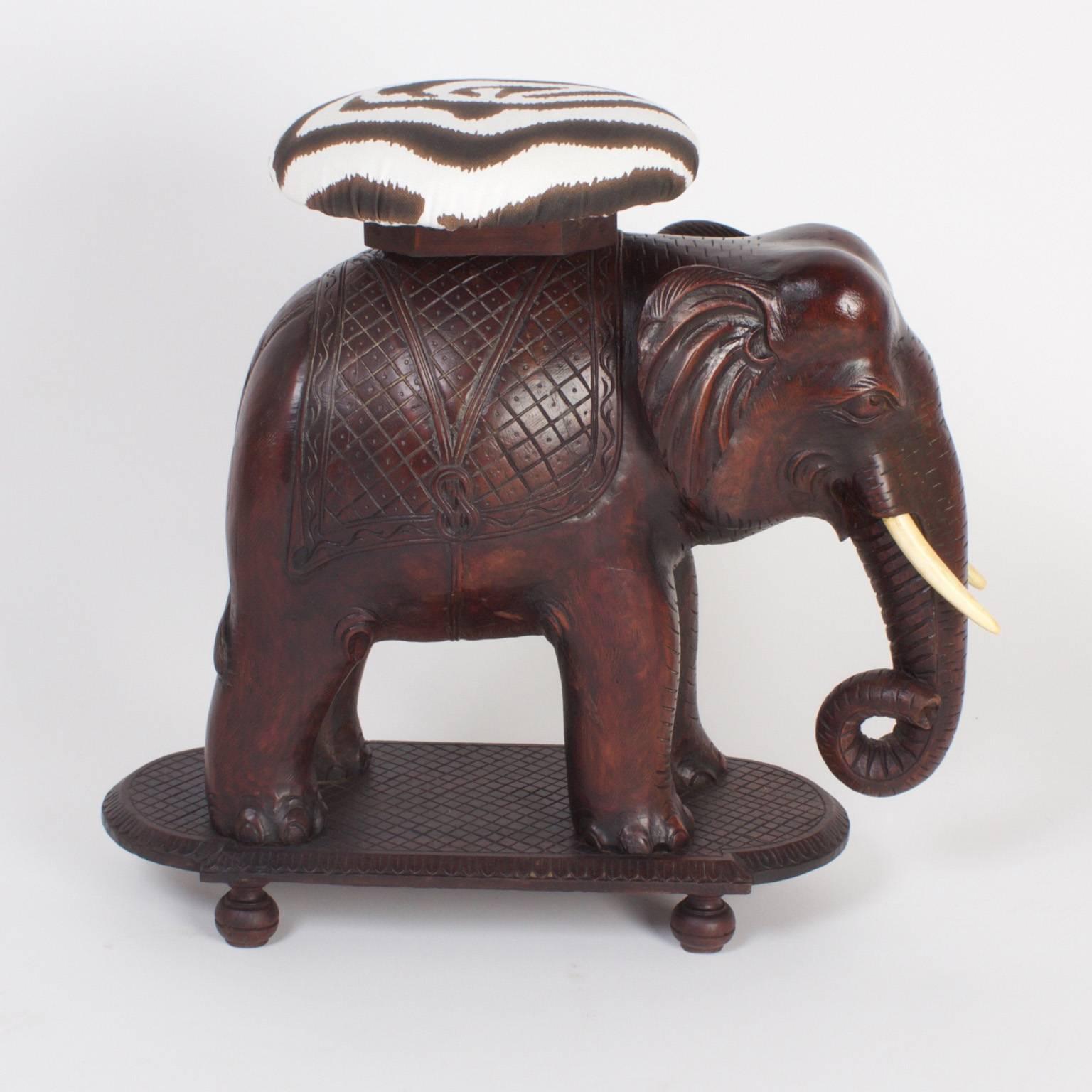 Impressive Anglo Indian elephant bench or seat carved from a single block of mahogany, presented with bone tusks on a carved platform over Classic turned feet.
  
