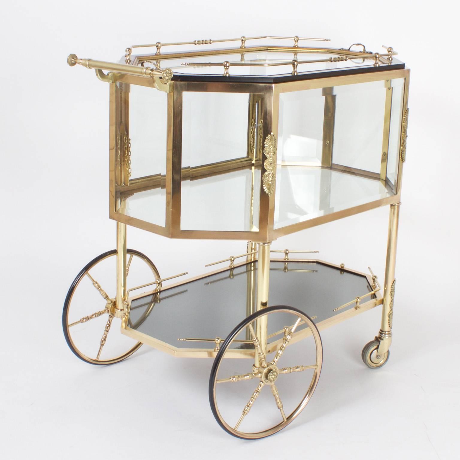 Chic, brass dessert cart or drink trolley with distinct continental flair. Featuring a removable serving tray, beveled glass display box with a hinged door, and lower plateau for extra storage all on decorative wheels. Best of its genre.
    