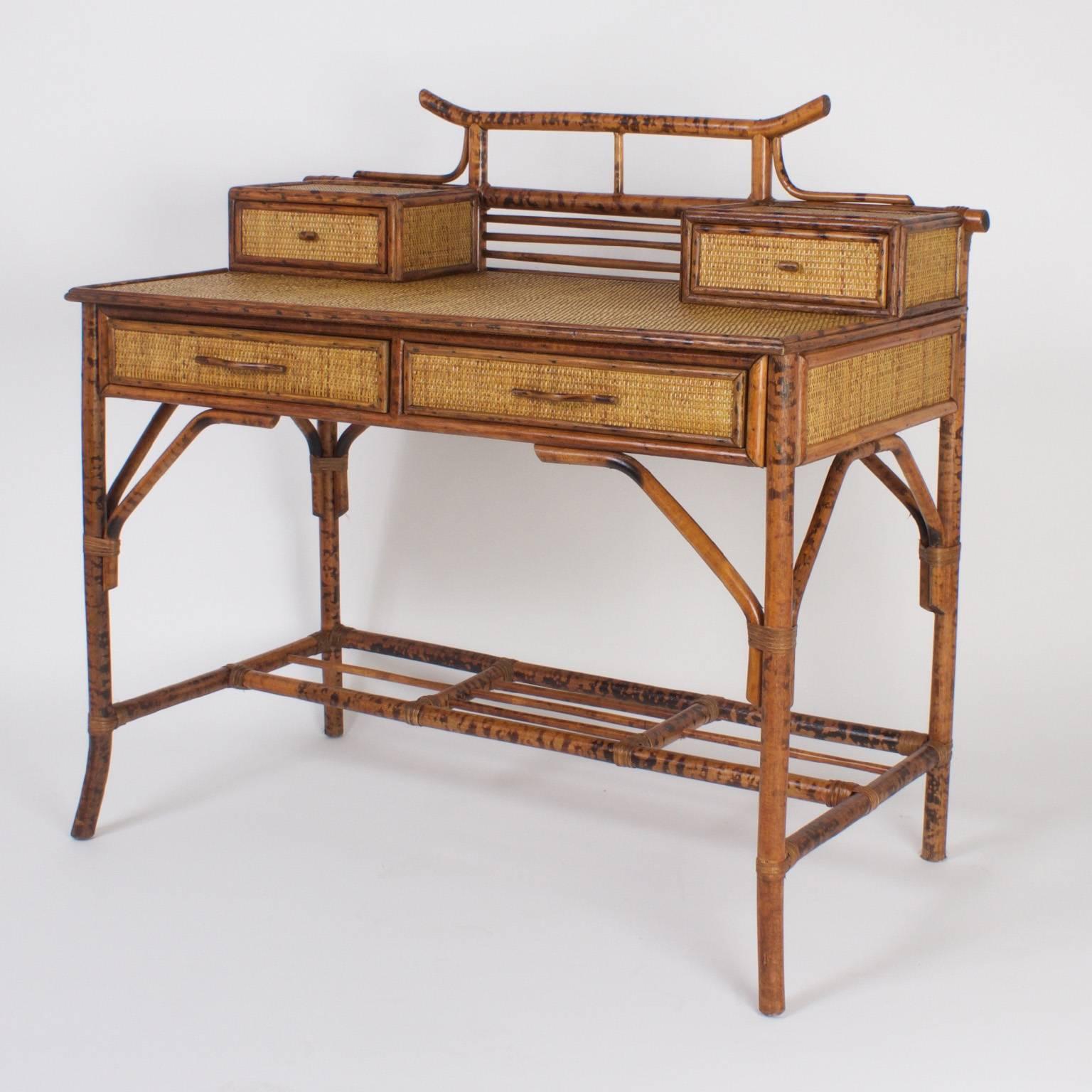 Brighton Pavillion style chinoiserie faux bamboo and grass cloth desk or writing table with matching caned seat chair, both having a distinctive pagoda ornament at the tops and Asian style splayed legs. 

Measures: Seat height 17.5.