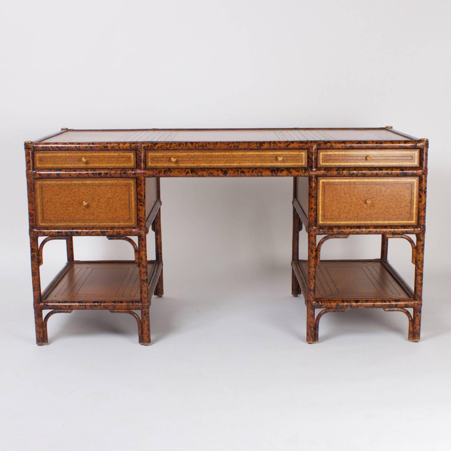 Impressive five drawer desk with a faux tortoise and bamboo frame and variegated, tooled and gilt tan leather panels on the top sides, drawer fronts and lower plateau.This desk is finished on all four sides. Signed Maitland-Smith in the middle