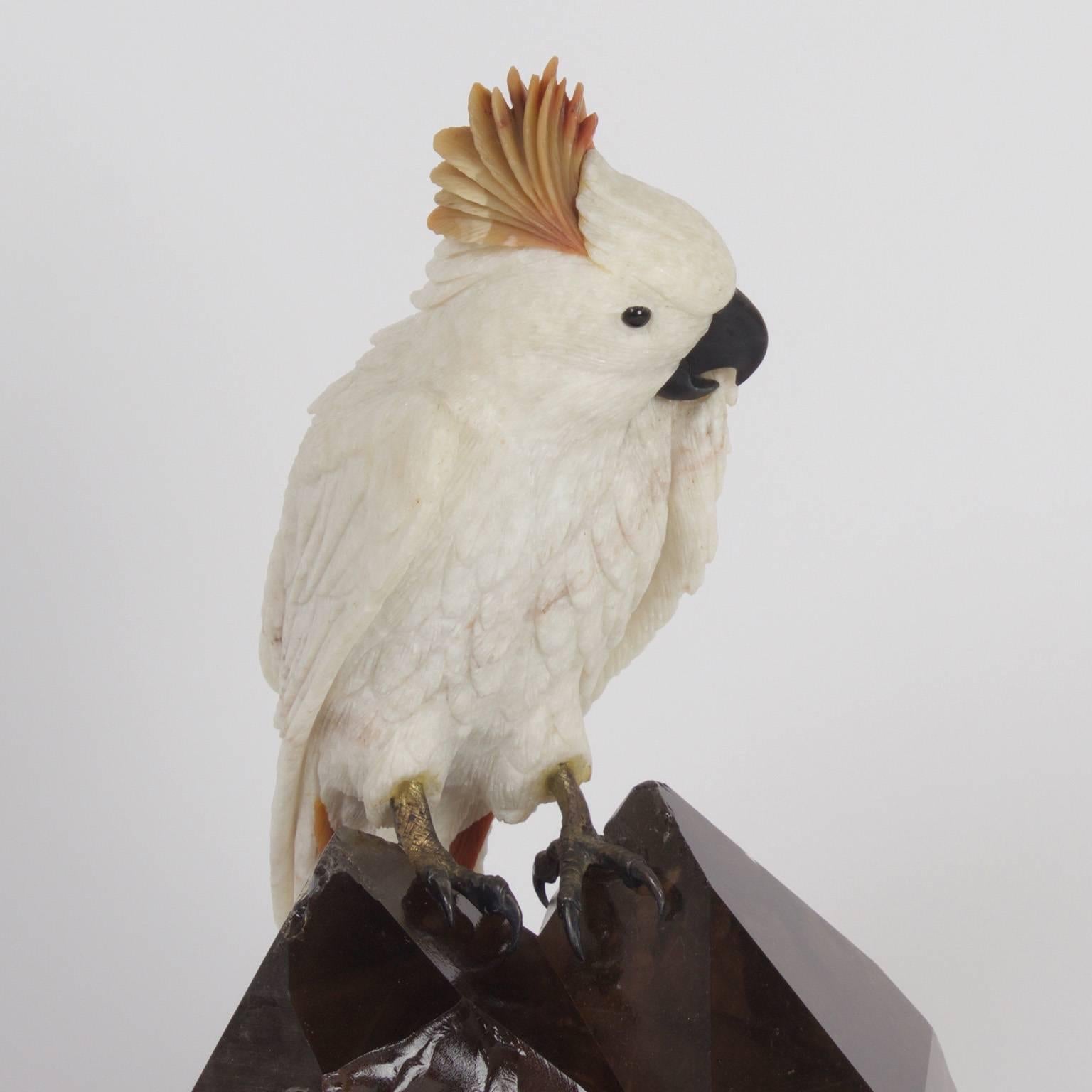 Amusing carved stone cockatoo with a quirky expression and brass feet mounted on an impressive smoky quartz specimen.

