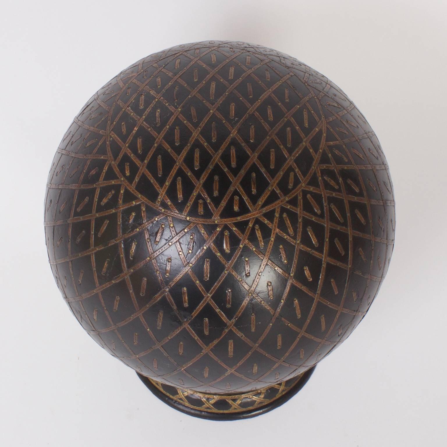 Unusual, vintage Anglo-Indian globe or orb crafted in ebonized wood and decorated in an elaborate well thought painted pattern. Presented on a classic brass clad stand.
  