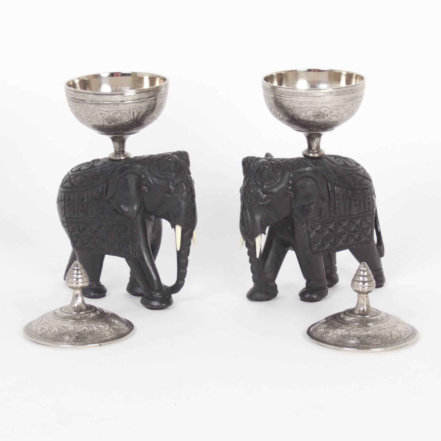 Antique tea caddies crafted from silvered metal and inscribed with intricate floral designs, presented on amusing, rustic carved hardwood elephants for your serving pleasure.
 