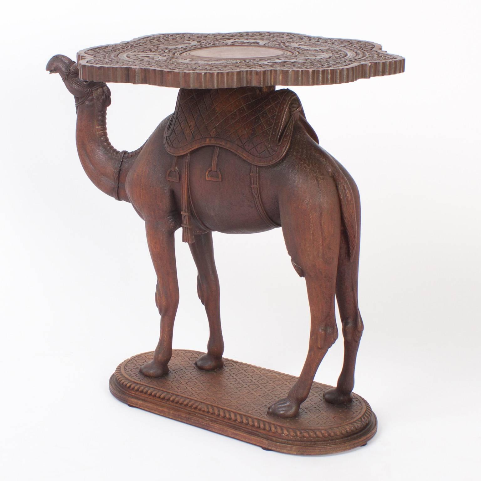 Inspired and rare antique Anglo Indian camel table carved from exotic hardwood with surprising attention to detail ,complete with a saddle supporting a floral carved table top.
