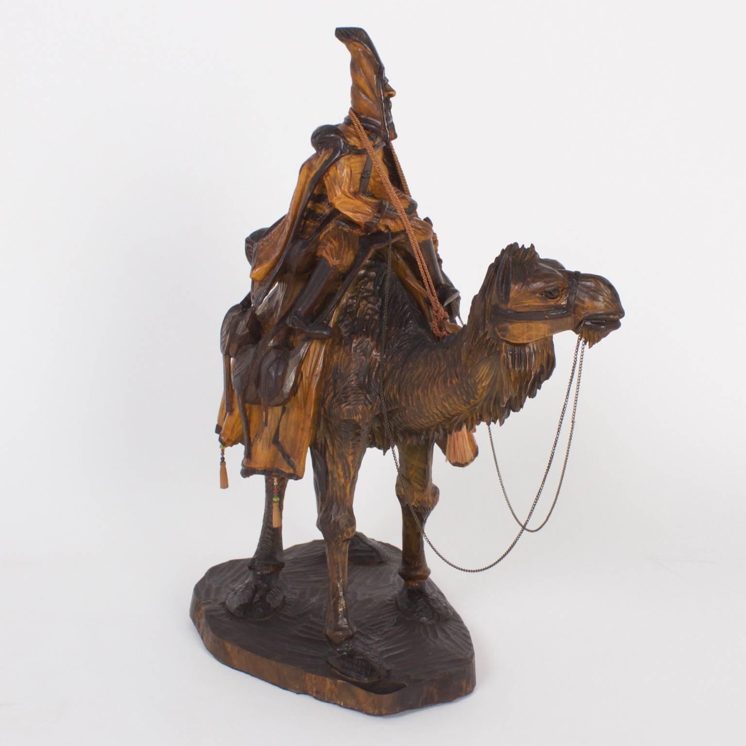 Rare and unusual early 20th century carved walnut figure of a Bedouin or desert nomad riding a camel and carrying everything one would need to live a free and easy lifestyle outside under the sun and stars.
  