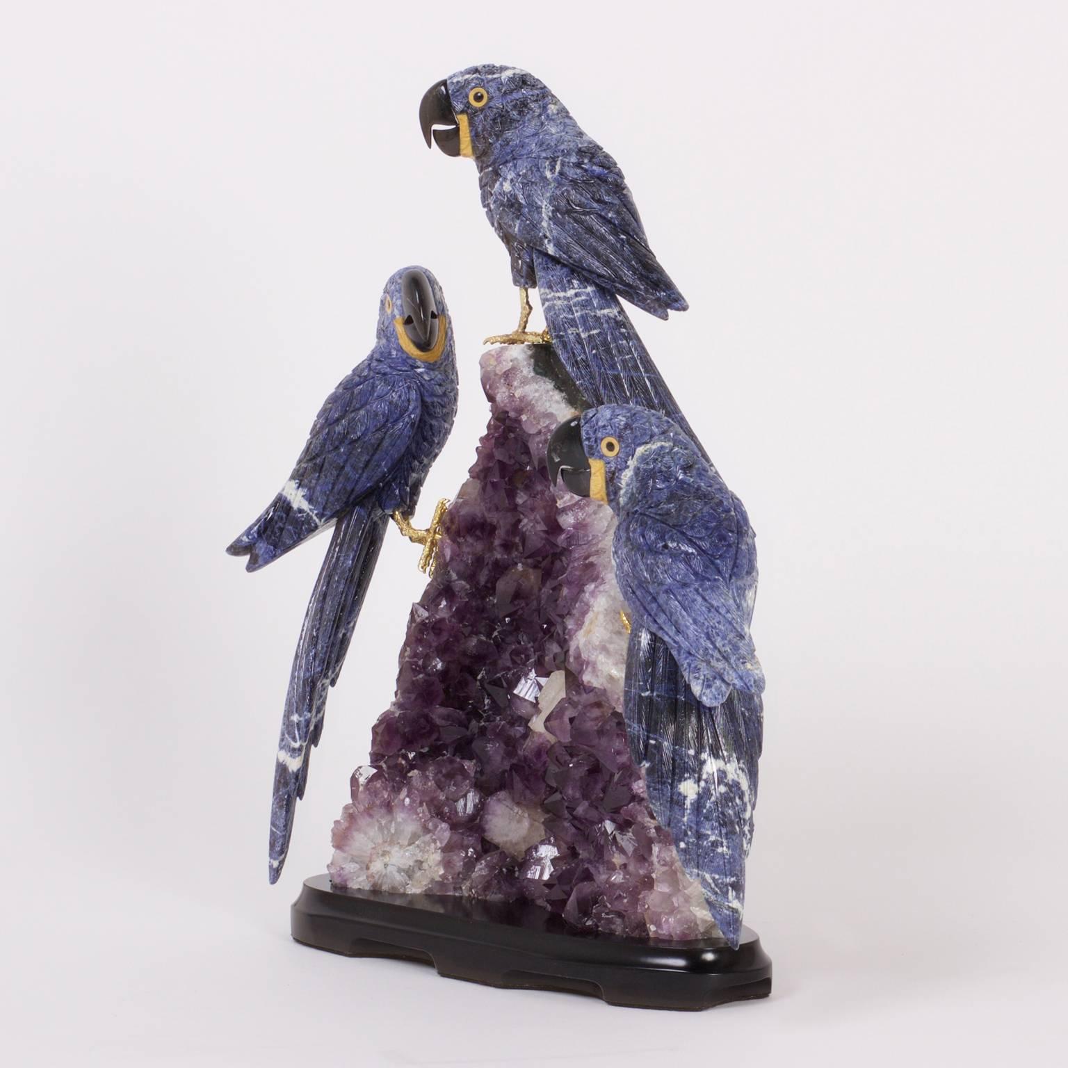 Fascinating sculpture of three fanciful parrots primarily carved of lapis lazuli with brass feet perched on an amethyst geode specimen with an ebonized wood stand. 

 