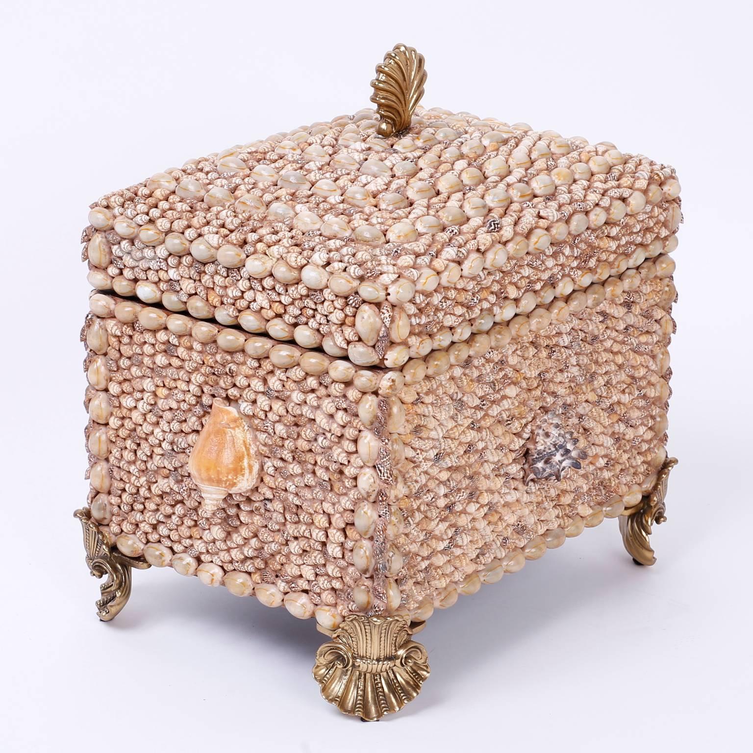 Lofty seashell encrusted lidded box with stylized shell feet and handle that reminds us of French ormolu. The inside of the box in lined with luxurious mahogany where it is labeled Maitland Smith on a brass plaque.
 