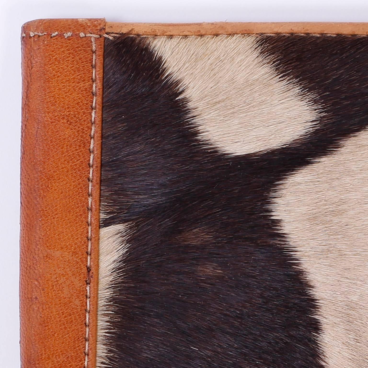 Swank, Mid-Century note pad cover crafted with zebra hide and soft tan leather. Cover can hold a cell phone in its pouch.

 