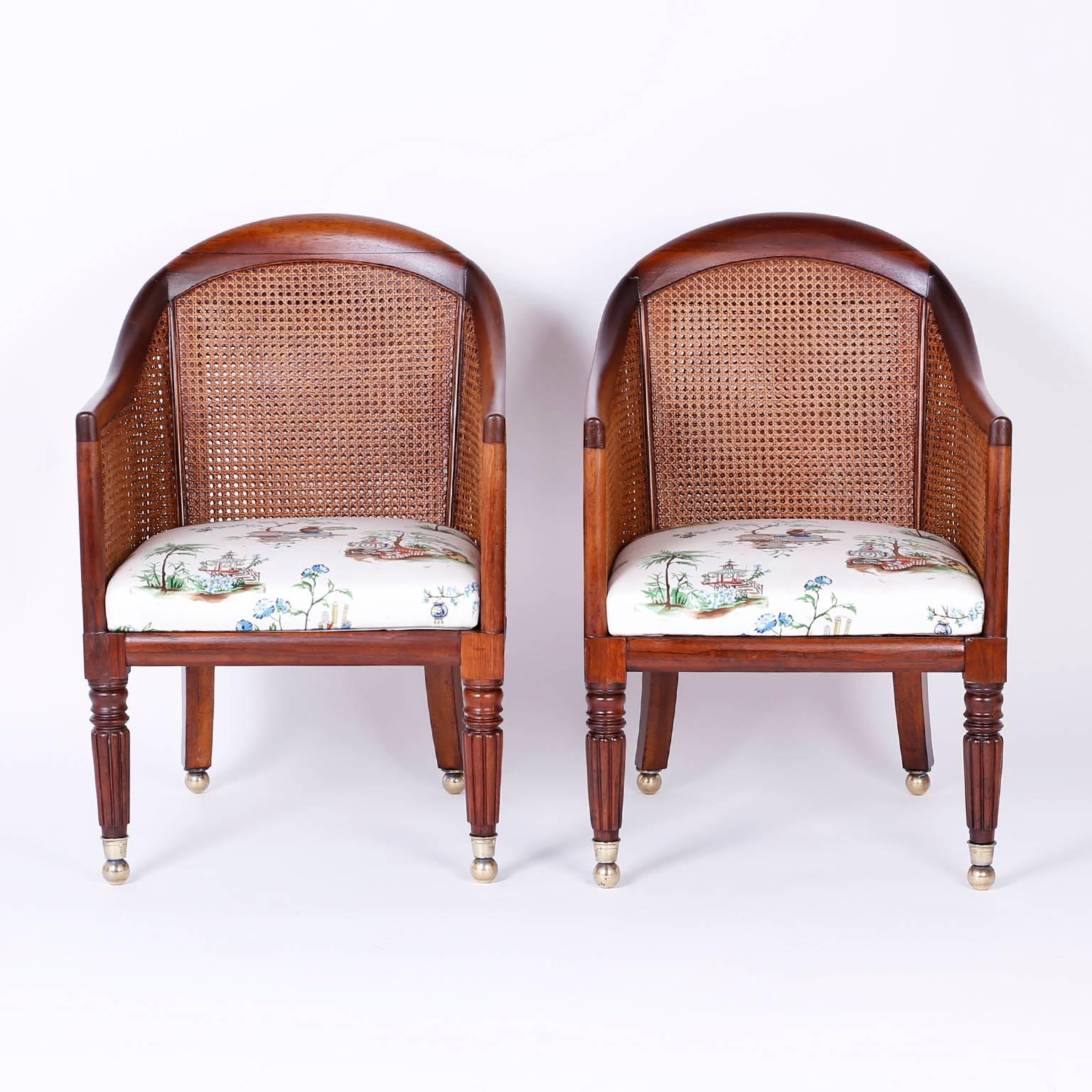 A fine pair of antique late Regency style English rosewood tub chairs that borrow influences from Directoire and Empire. The back and sides are double caned to breathe with maximum durability. The bold front legs are lathe turned and reeded, the