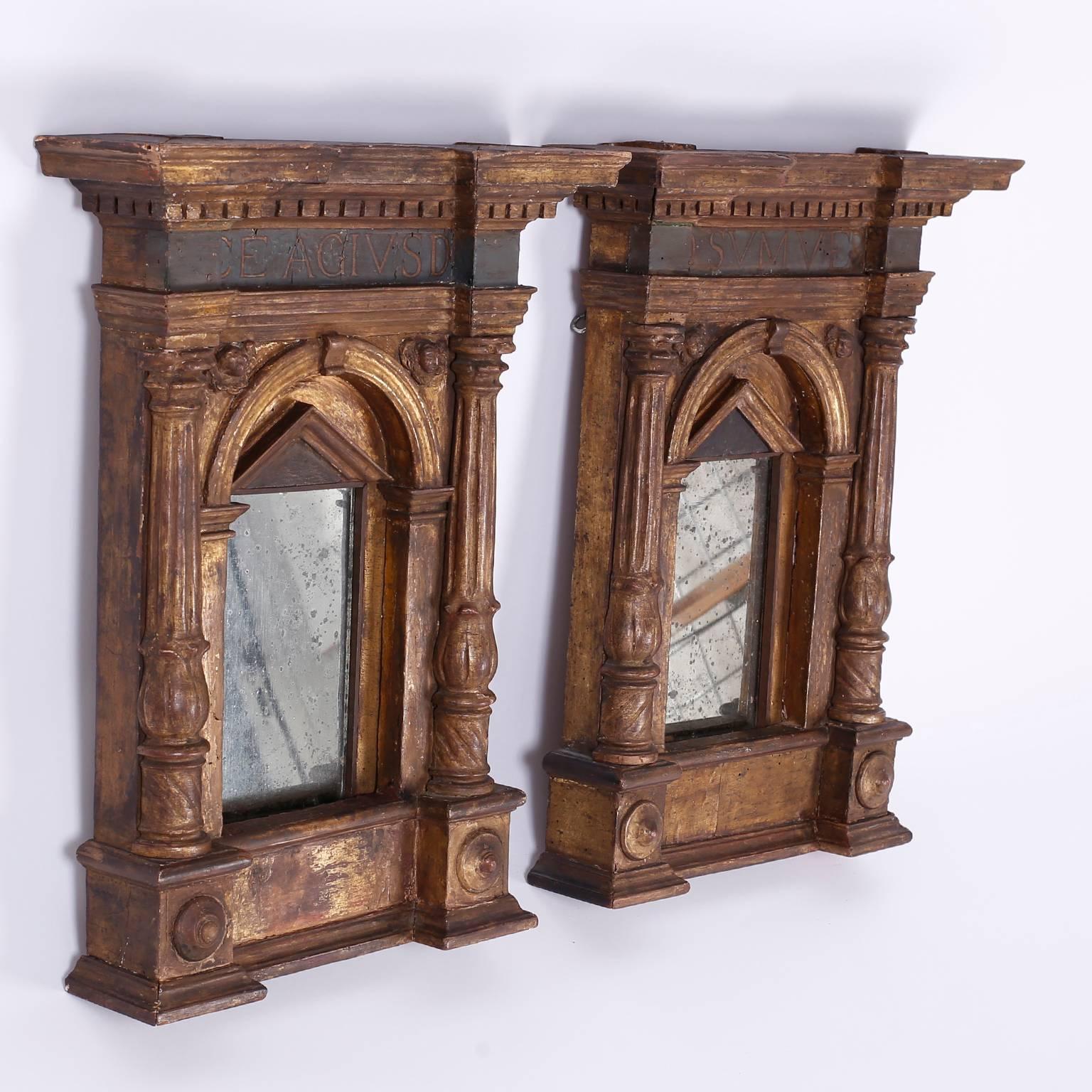 Pair of historically relevant mirrors. Transporting Renaissance mirror frames carved from walnut and retaining their 17th century gilt gesso. Featuring the unrestrained influence of Classic Greek architecture and decorated with Latin descriptions.