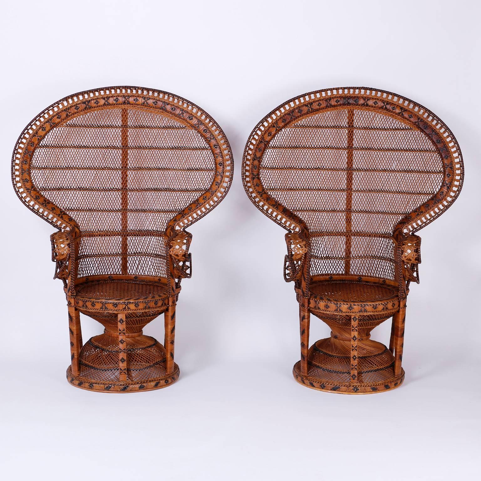 Here is a fine pair of Mid-Century peacock armchairs with their iconic form and exotic ambiance. Handcrafted in wicker and reed, decorated with geometric designs similar to snake skin, all in a mellow aged patina. These Classic chairs are in
