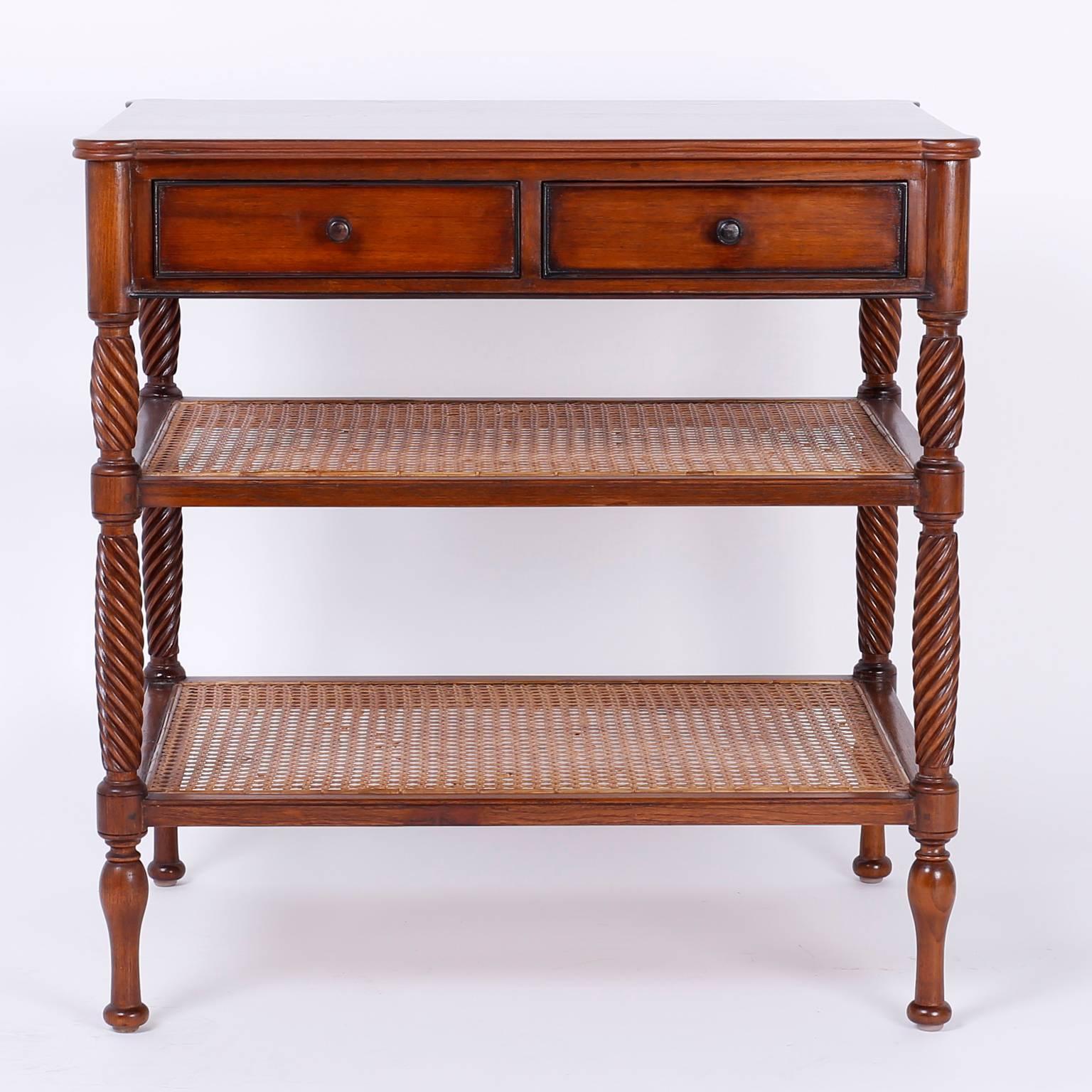 Handsome, vintage mahogany side table or console with a West Indian vibe. Featuring a two drawer case above two caned shelves with elegant turned and carved supports that give this piece authentic, tropical, British Colonial appeal.