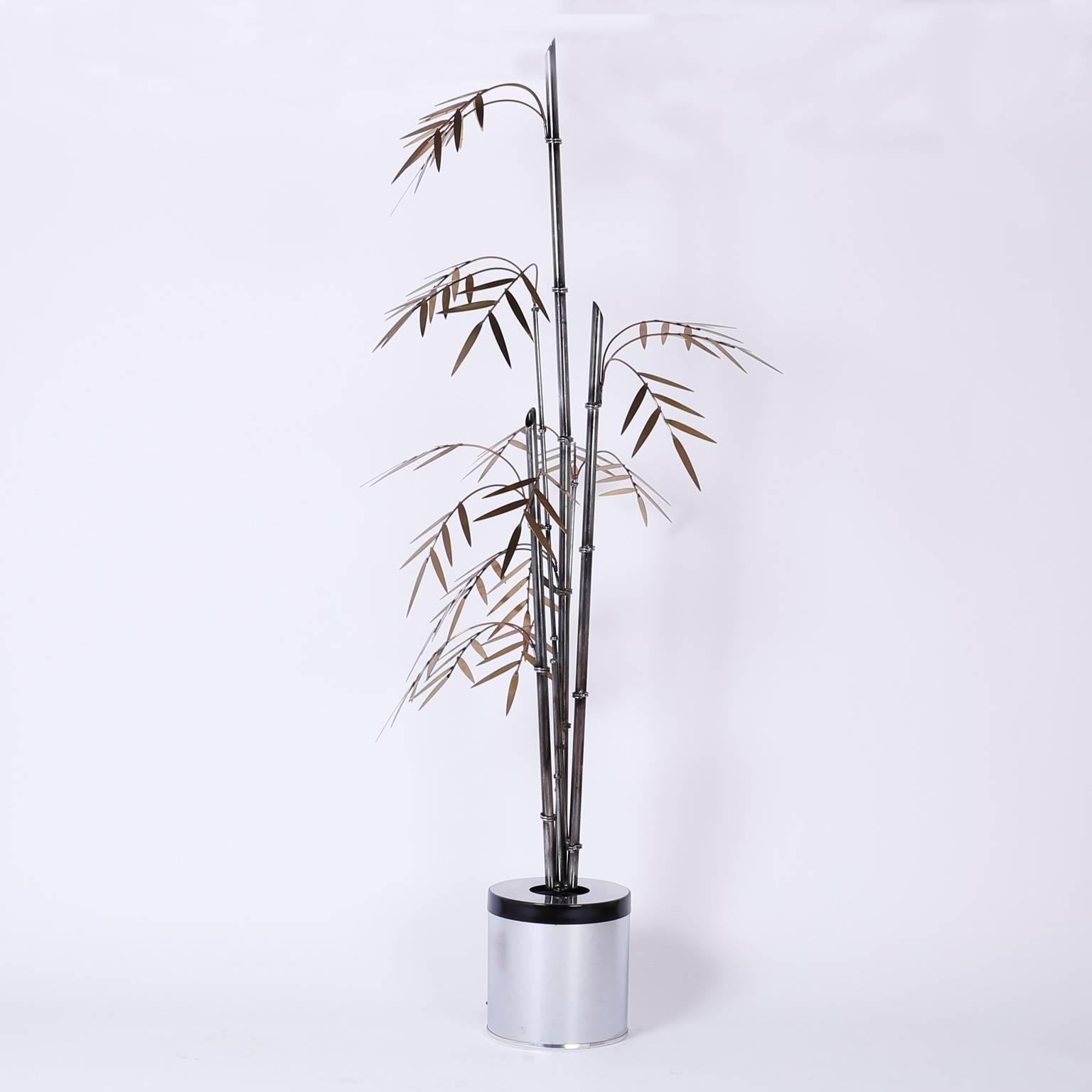 Chic, tropical palm style bamboo sculpture crafted with iron bamboo shoots in varying stages of development and copper and brass stylized branches and leaves. The canister base has a one bulb socket that can create subtle mood lighting.
