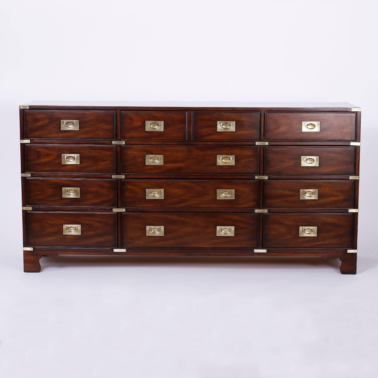 Handsome and unusual 12-drawer mahogany chest of drawers crafted in the Mid-Century with a simple, yet bold profile, clad with Campaign style brass hardware hand polished and lacquered for easy care. Signed Heritage in drawer.