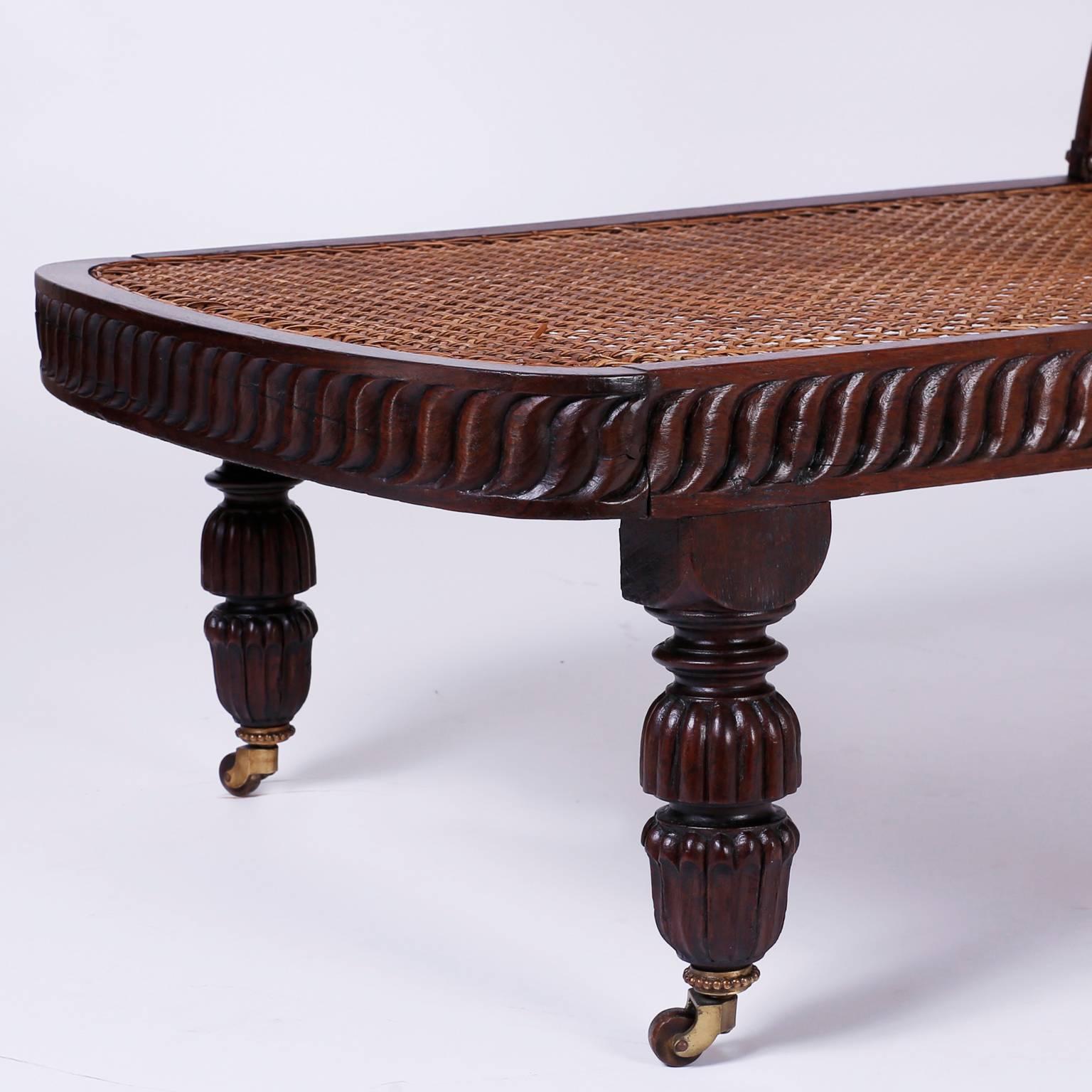 Spirited carved mahogany chaise or recamier, from the West Indies, with elegant classic form. Inspired by the sea with graceful wavy lines and carved nautilus shells surrounding a star medallion. Hand caned seat, back, and side over four double