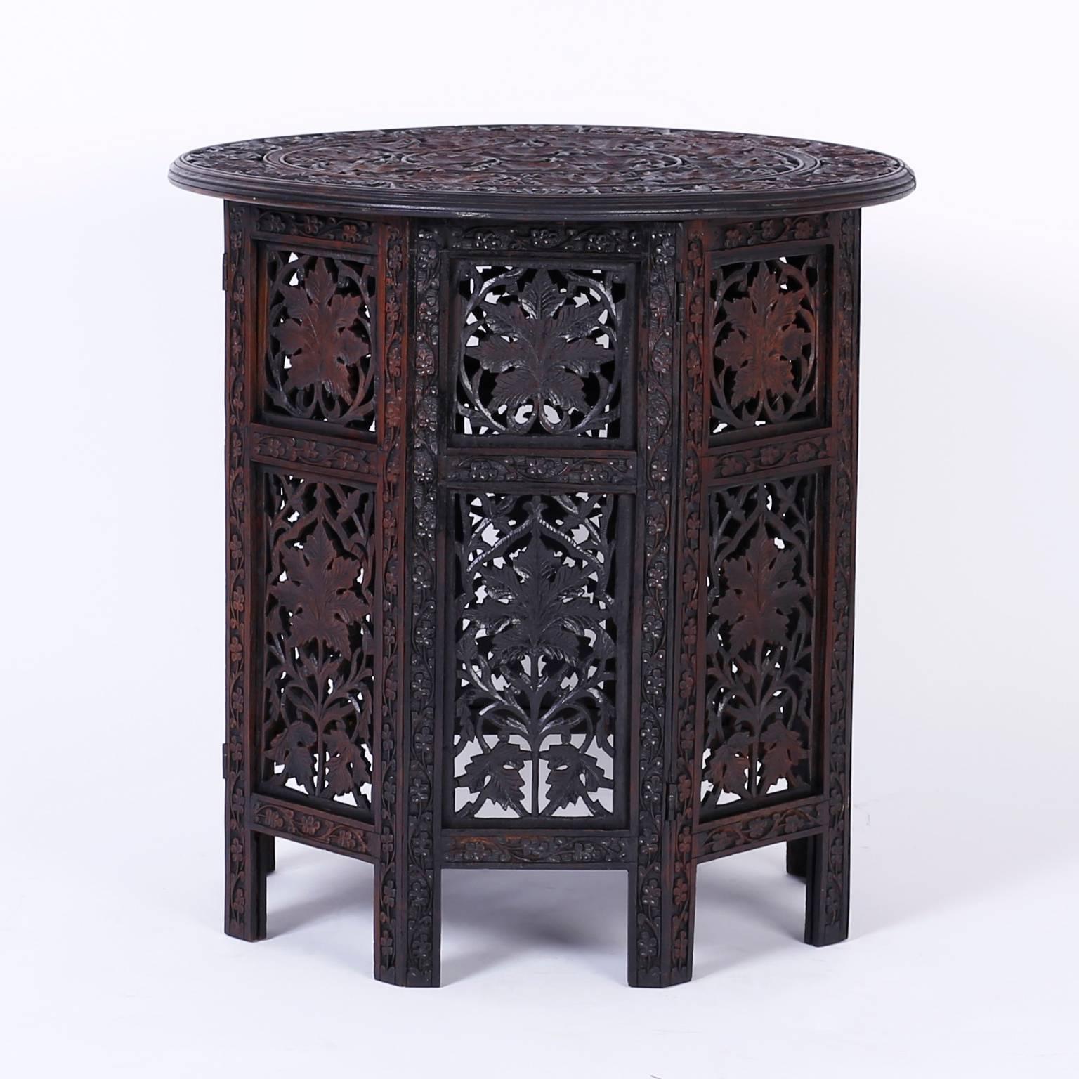 Intriguing pair of elaborately carved Anglo-Indian end or occasional tables with circular tops carved in a leaf and berry motif and an octagon paneled base with carved open fret work leaf designs.