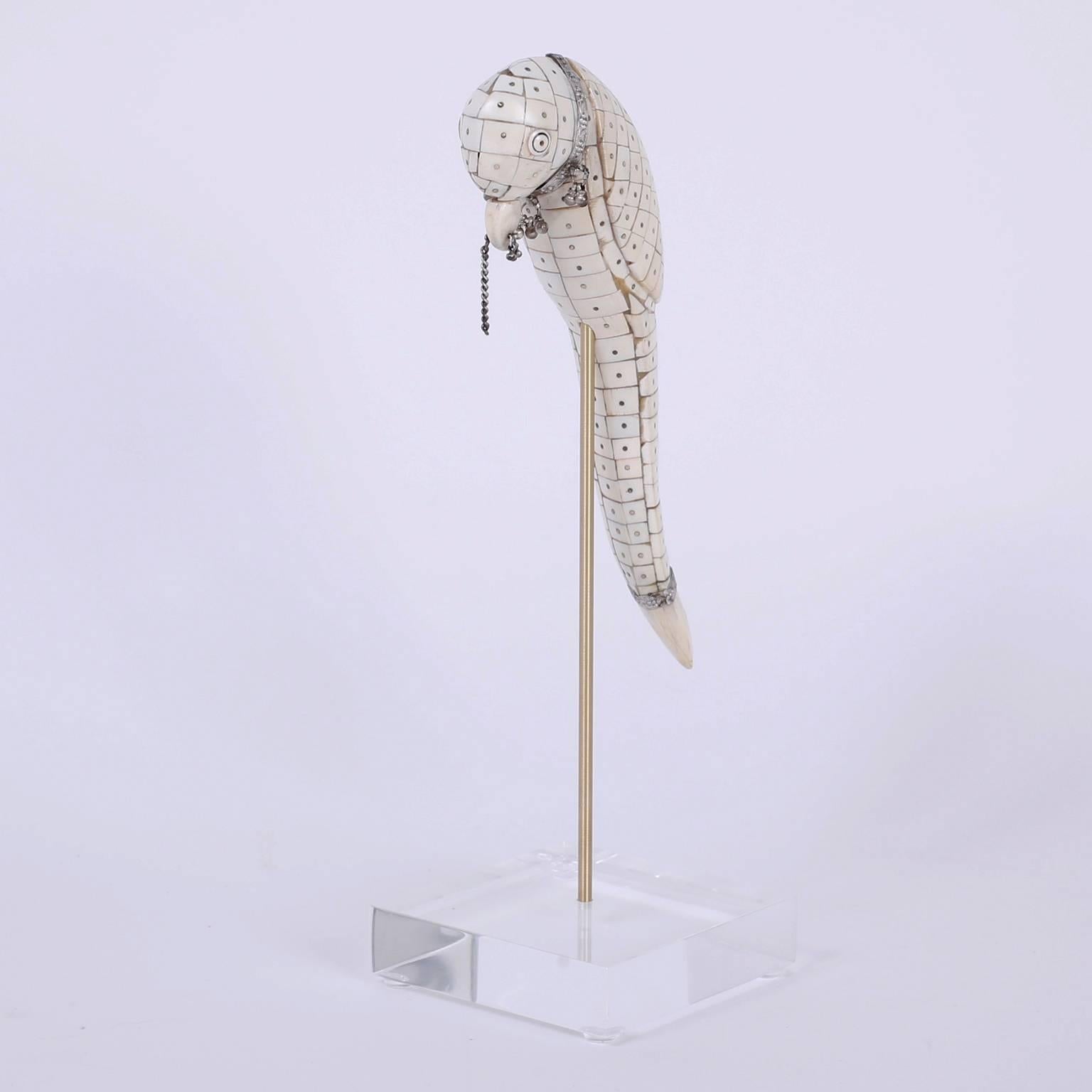 Intriguing Anglo-Indian Parrot sculpture skillfully crafted with a mosaic of ox bone fragments. This stylish bird is sporting hand-hammered silver jewelry including a nose ring, all this presented on a brass rod and Lucite base.