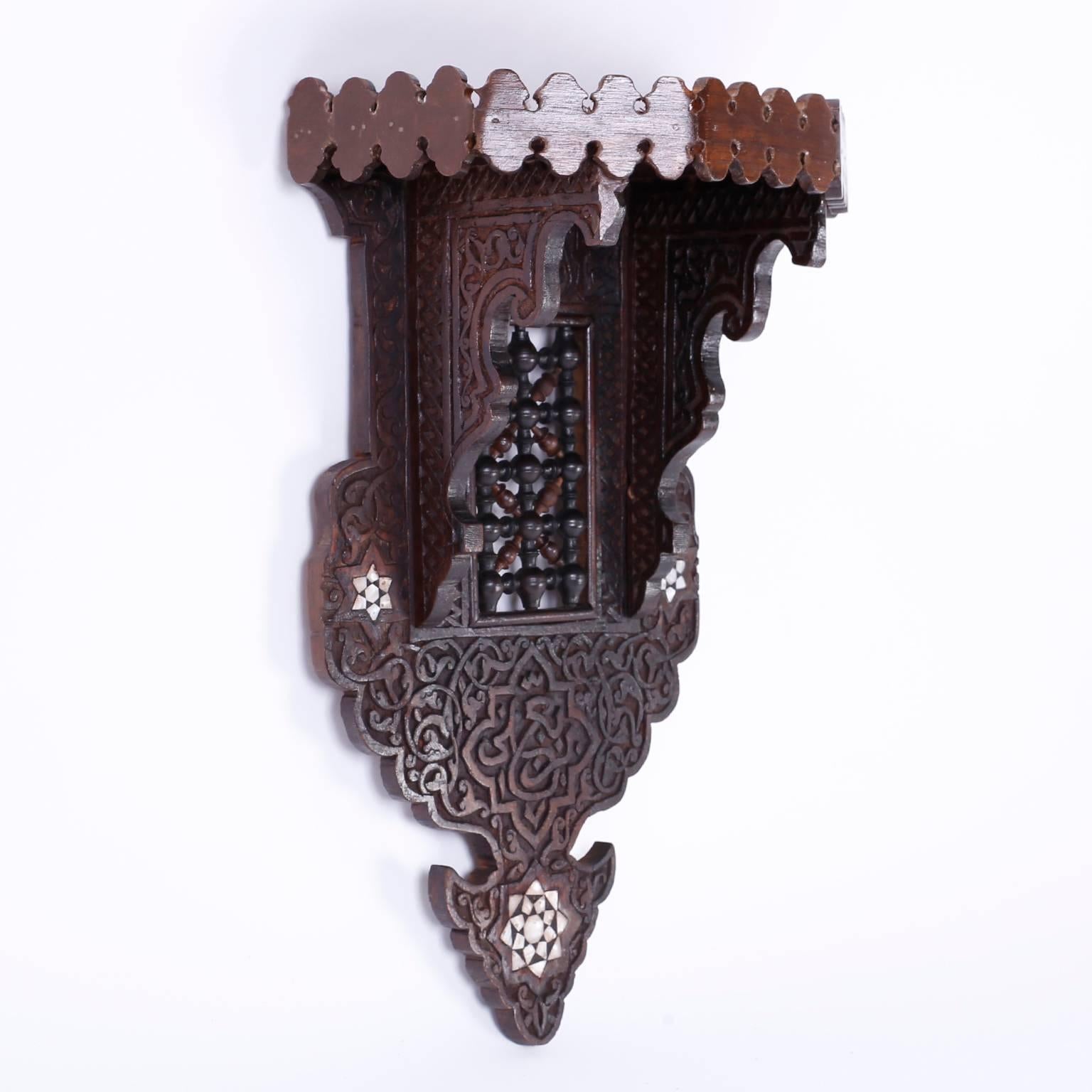 Fascinating Moroccan wall bracket with a rampart gallery around the shelf, elaborate floral carvings, a stick and ball center panel and three inlaid mother-of-pearl stars.