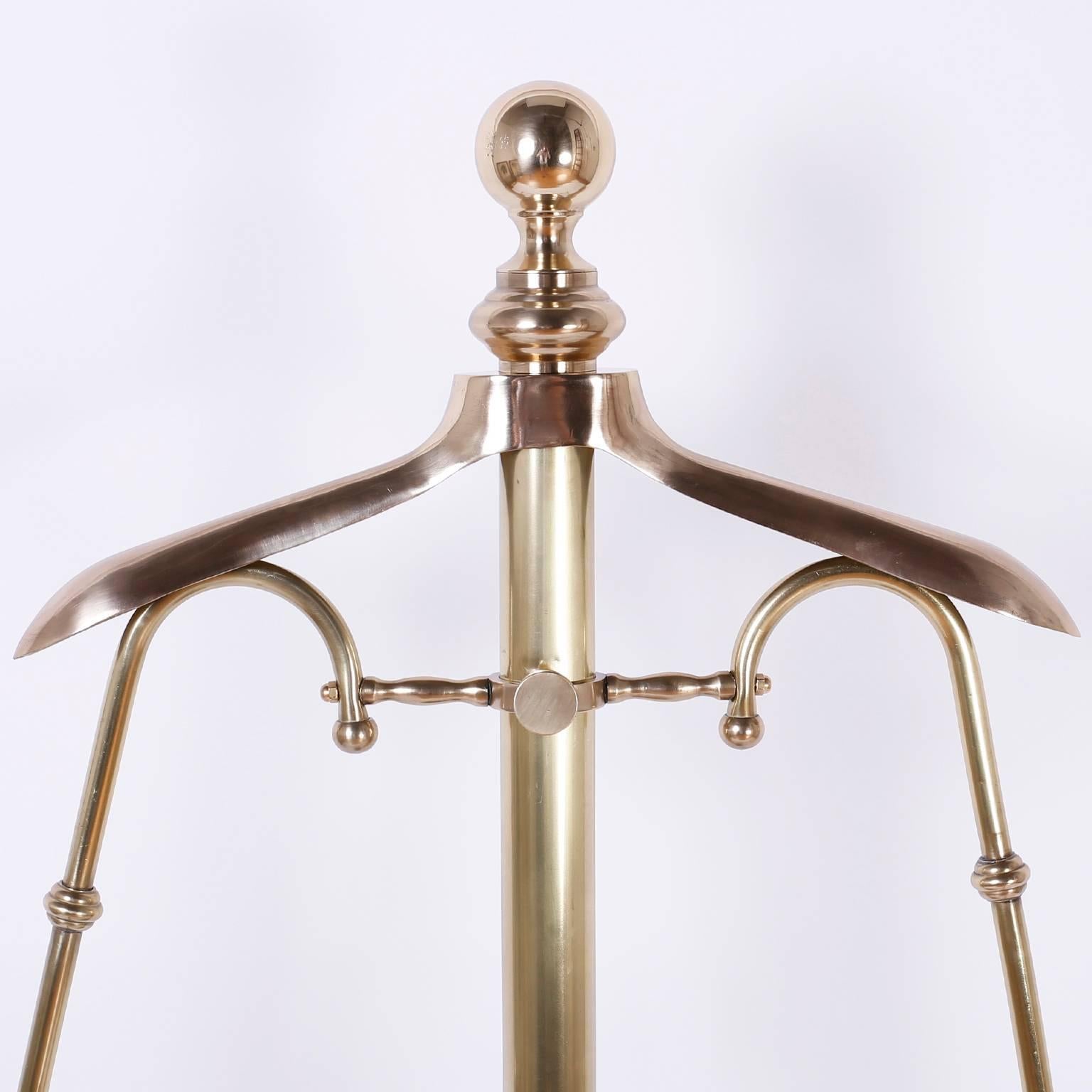 Edwardian silent butler or gentlemen's valet crafted in brass with hangers for a shirt, jacket, trousers and a dish for loose change or jewelry. The base has classic scrolled feet around a circular stretcher.